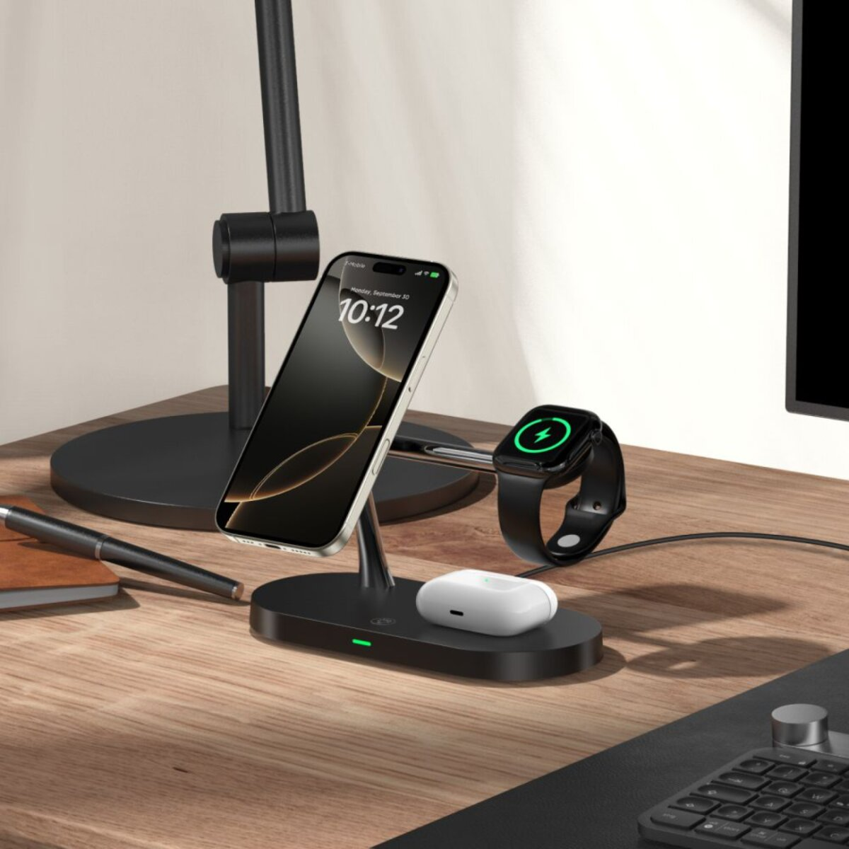 Une station de recharge pour téléphone, montre connectée et écouteurs. Le téléphone affiche l'heure. Un stylo et un carnet sont sur un bureau en bois.