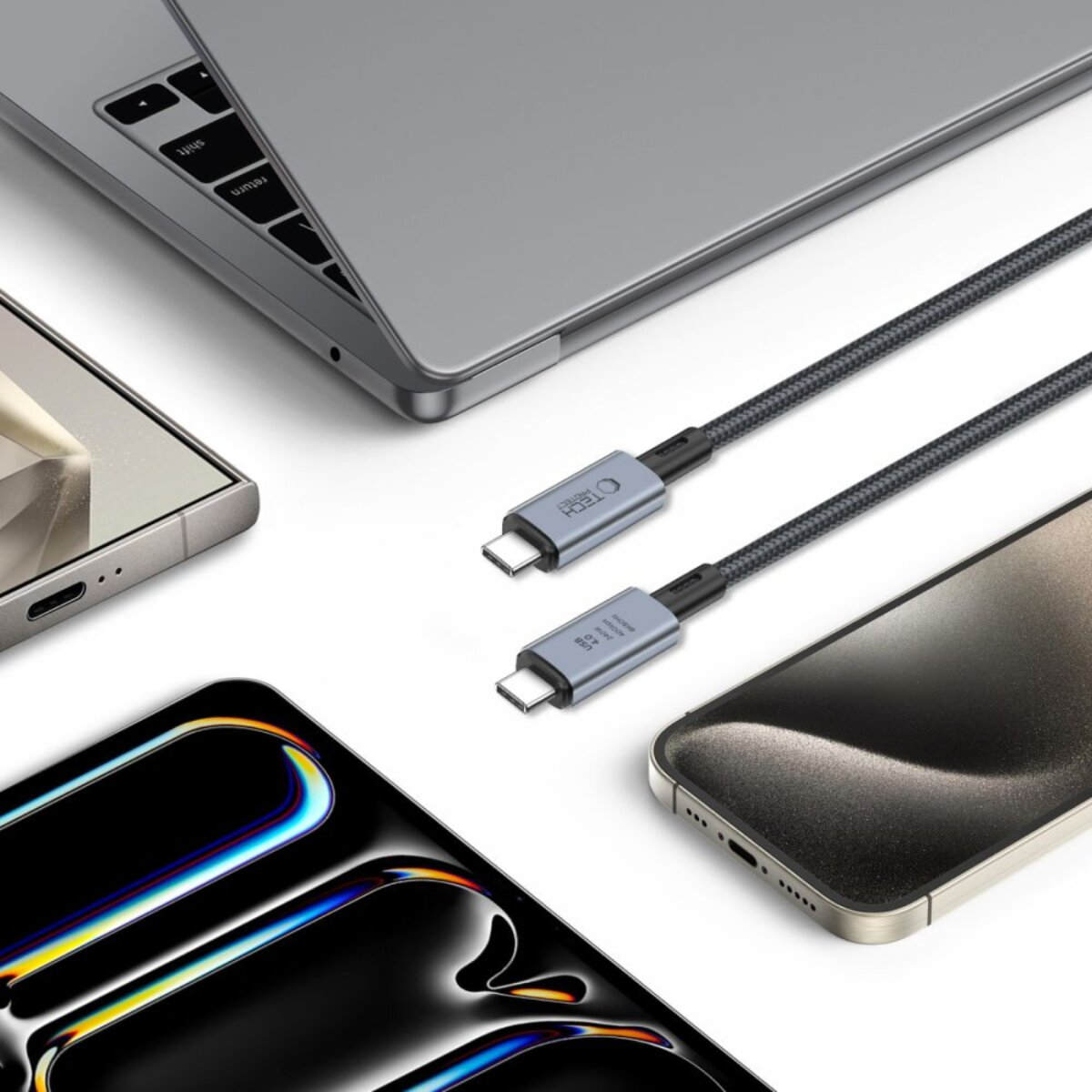 Deux câbles USB-C, un ordinateur portable et deux smartphones sont affichés. Les câbles sont gris et noirs. L'ordinateur portable est argenté. Les téléphones sont noirs et dorés.