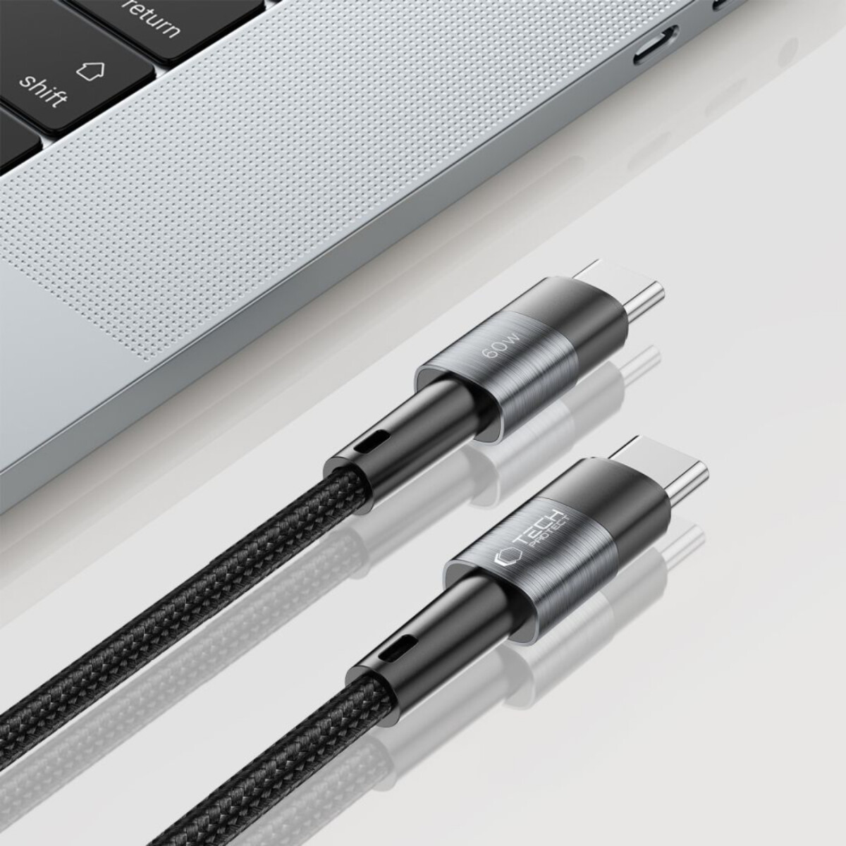 Deux câbles USB-C noirs avec des connecteurs argentés sont placés près d'un ordinateur portable. Les câbles ont un design tressé et sont étiquetés '60W' et 'TECH protect'.