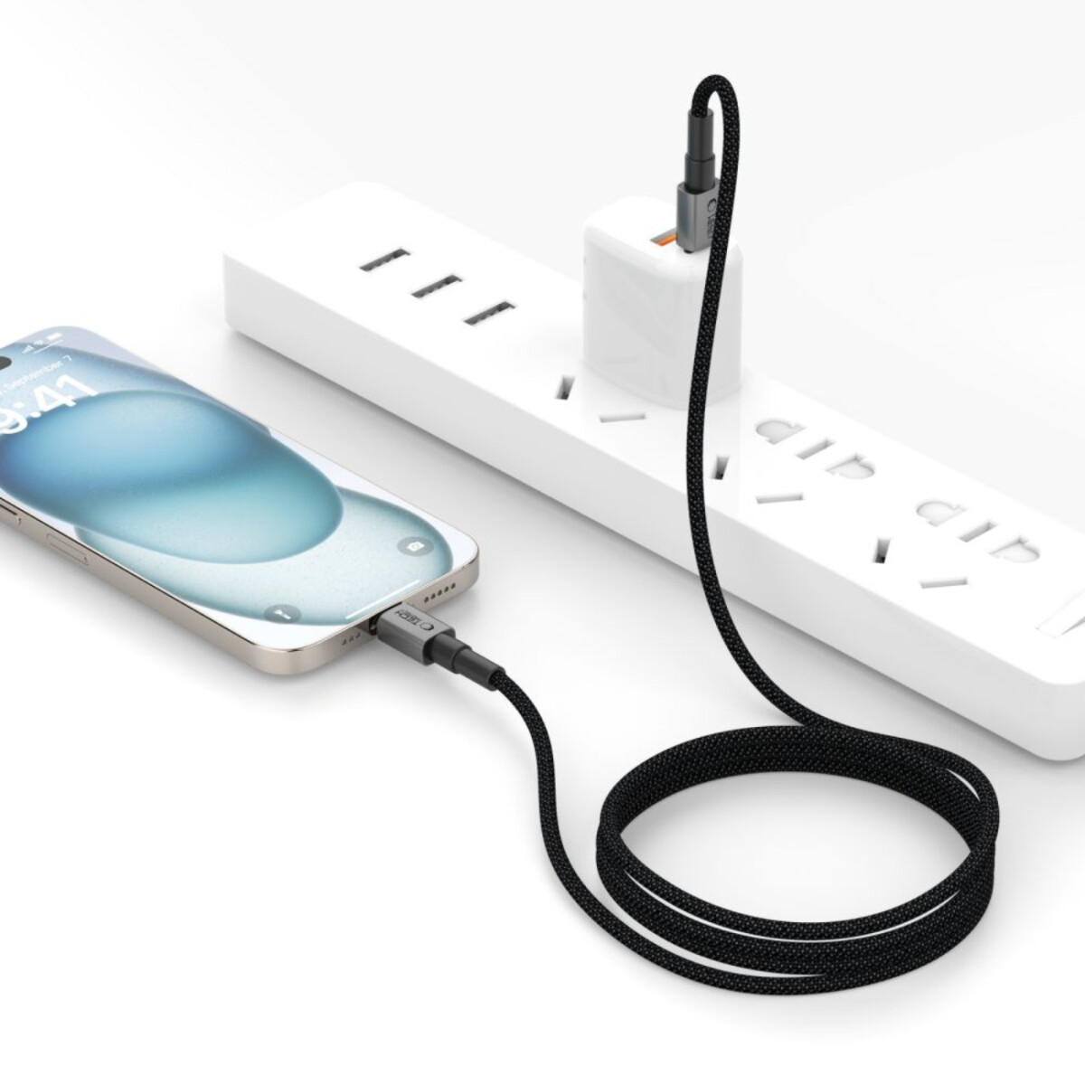 A phone is charging with a black cable. The cable is connected to a power strip and a white charging adapter.