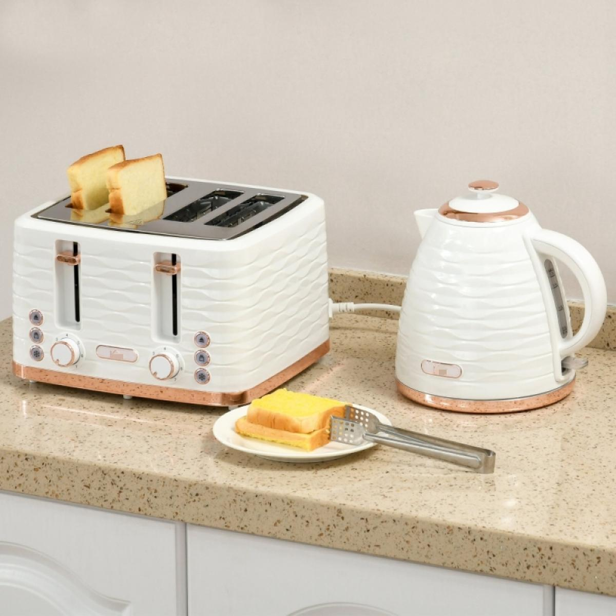 Ein weißer Toaster mit Brot, ein Wasserkocher und Toast auf einem Teller mit Zangen auf einer gesprenkelten Arbeitsplatte.