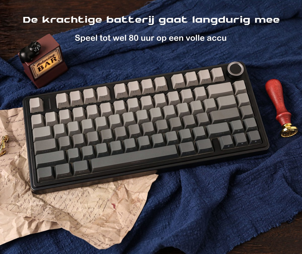 Eine Tastatur mit grauen Tasten liegt auf einem blauen Tuch. Ein kleines Barschild und ein roter Stempel sind im Hintergrund.