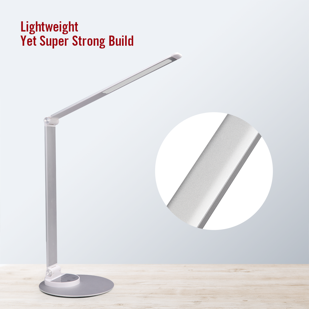 Eine moderne silberne Schreibtischlampe mit rechteckigem Leuchtkopf und rundem Fuß steht auf einer Holzoberfläche.
