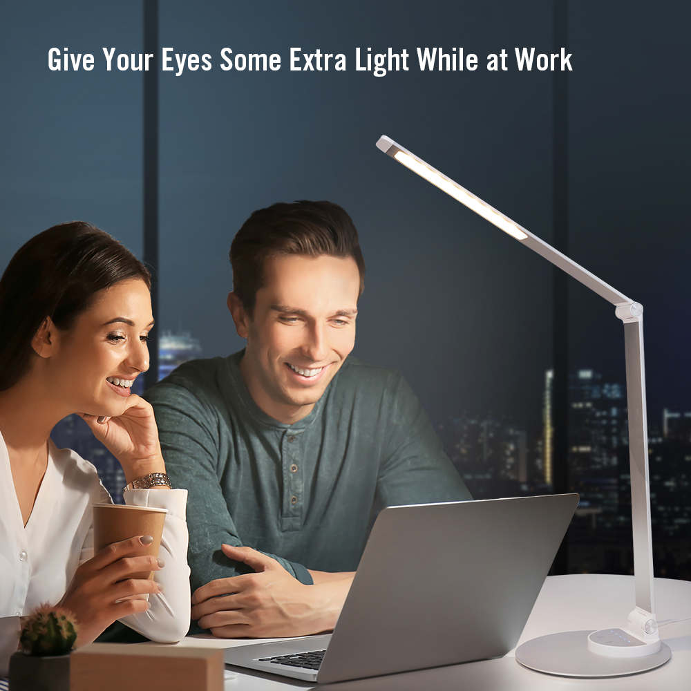 Ein Mann und eine Frau lächeln einen Laptop an, beleuchtet von einer Schreibtischlampe. Im Hintergrund ist eine Stadtlandschaft zu sehen.
