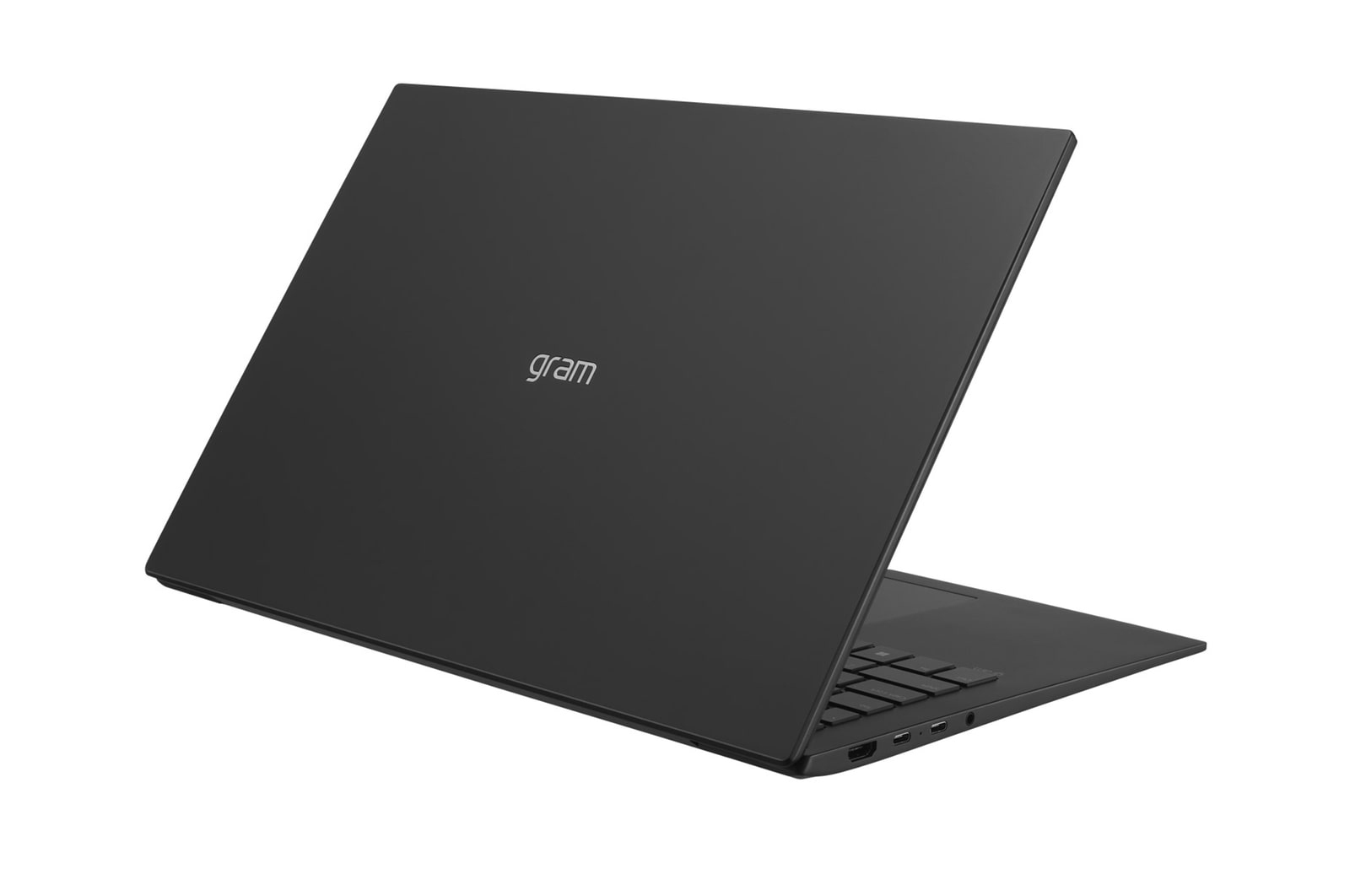 Un laptop nero è leggermente aperto, mostrando tastiera e porte. La parola 'gram' è stampata sul coperchio.