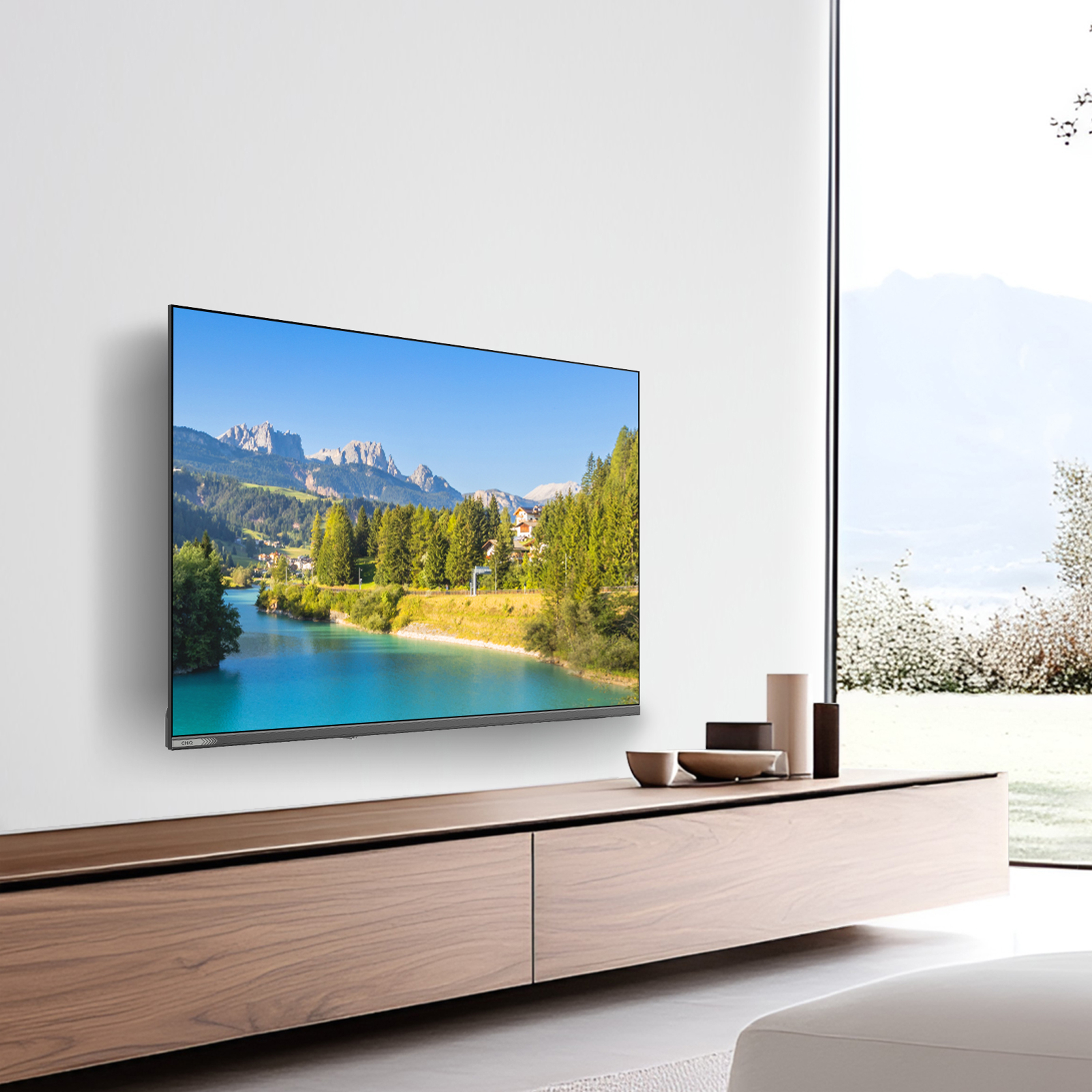 A TV displays a mountain lake scene. It's mounted on a white wall above a wooden cabinet. A window is on the right.