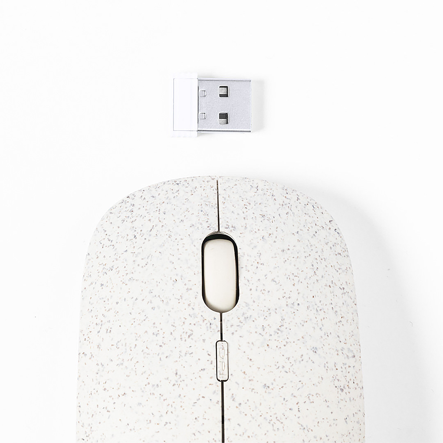 Un ratón blanco moteado con un receptor USB sobre una superficie blanca. El ratón tiene una rueda de desplazamiento y dos botones.