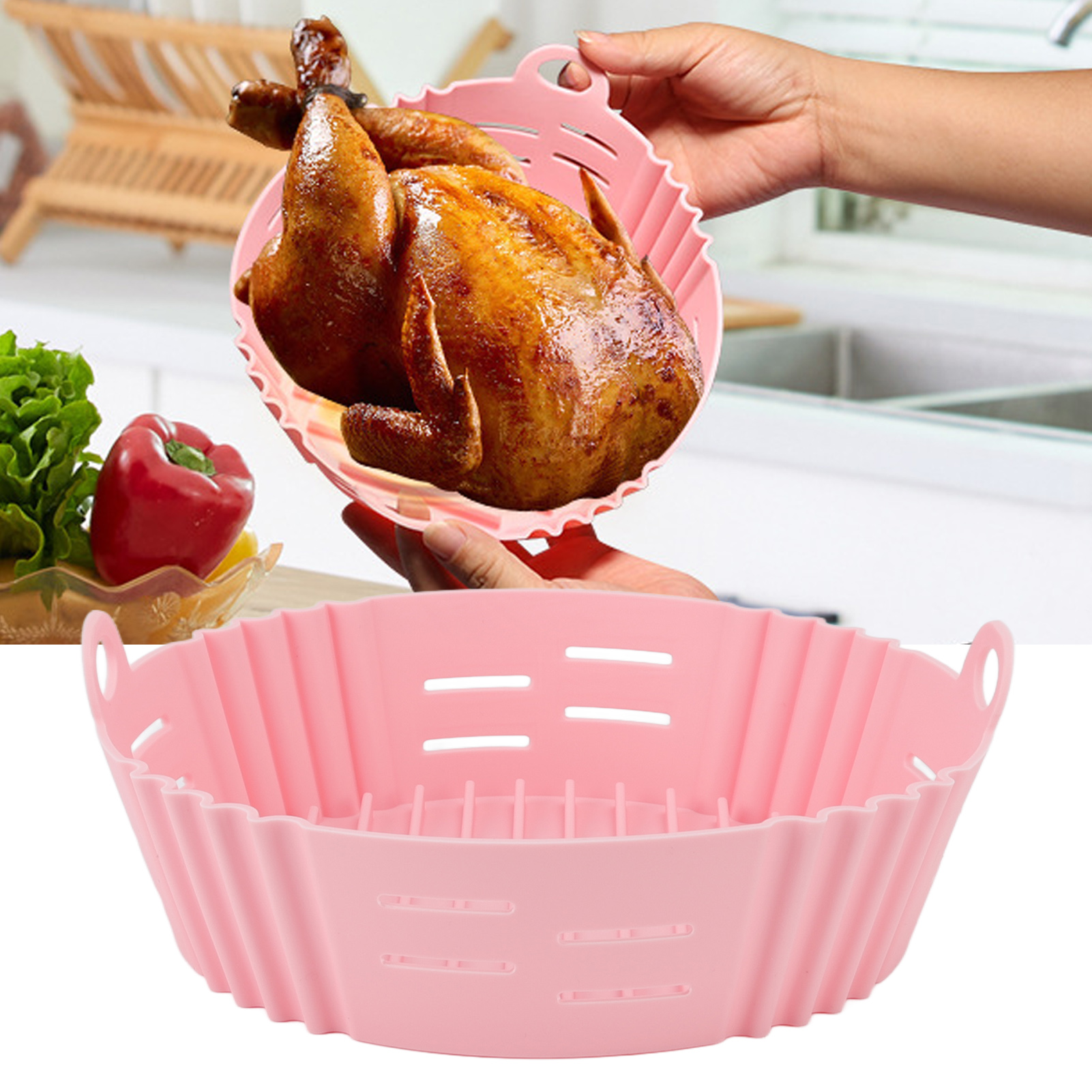 Ein gebratenes Hähnchen in einem rosa Silikonkorb wird von Händen gehalten. Ein ähnlicher Korb befindet sich darunter. Gemüse im Hintergrund.