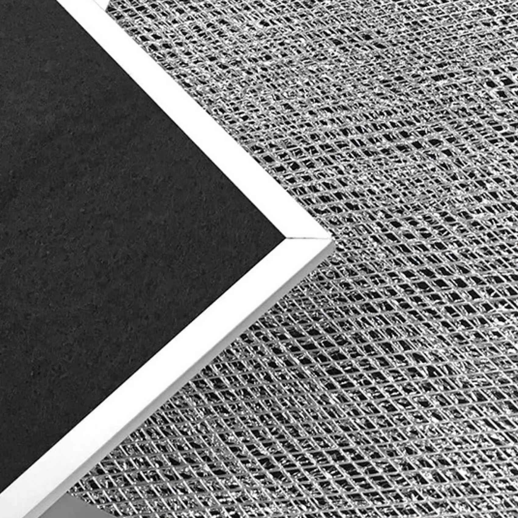 Nahaufnahme eines schwarzen Filters mit weißem Rahmen und einem Metallgitter. Der Filter ist abgewinkelt.