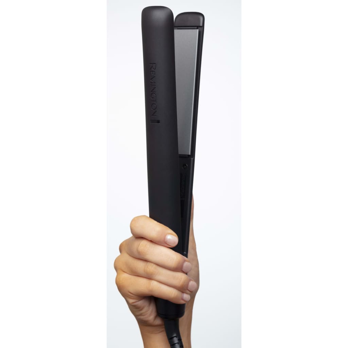 Ręka trzyma czarną prostownicę do włosów. Prostownica jest otwarta, odsłaniając srebrną płytkę. Tło jest białe.