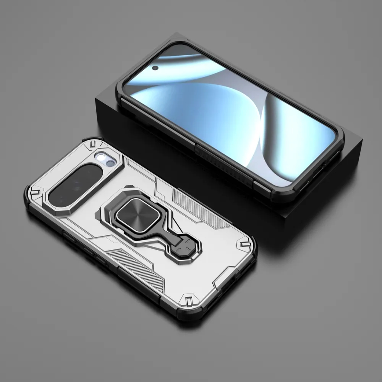 Twee telefoonhoesjes, één zilver met een ringhouder en één zwart op een zwart blok, het scherm zichtbaar.