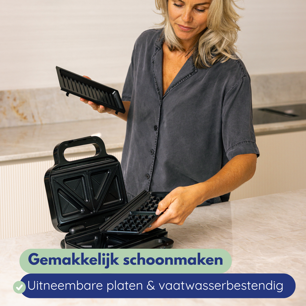 Een vrouw houdt wafelijzerplaten vast. De platen zijn zwart. De tekst luidt: gemakkelijk schoon te maken en vaatwasserbestendige platen.