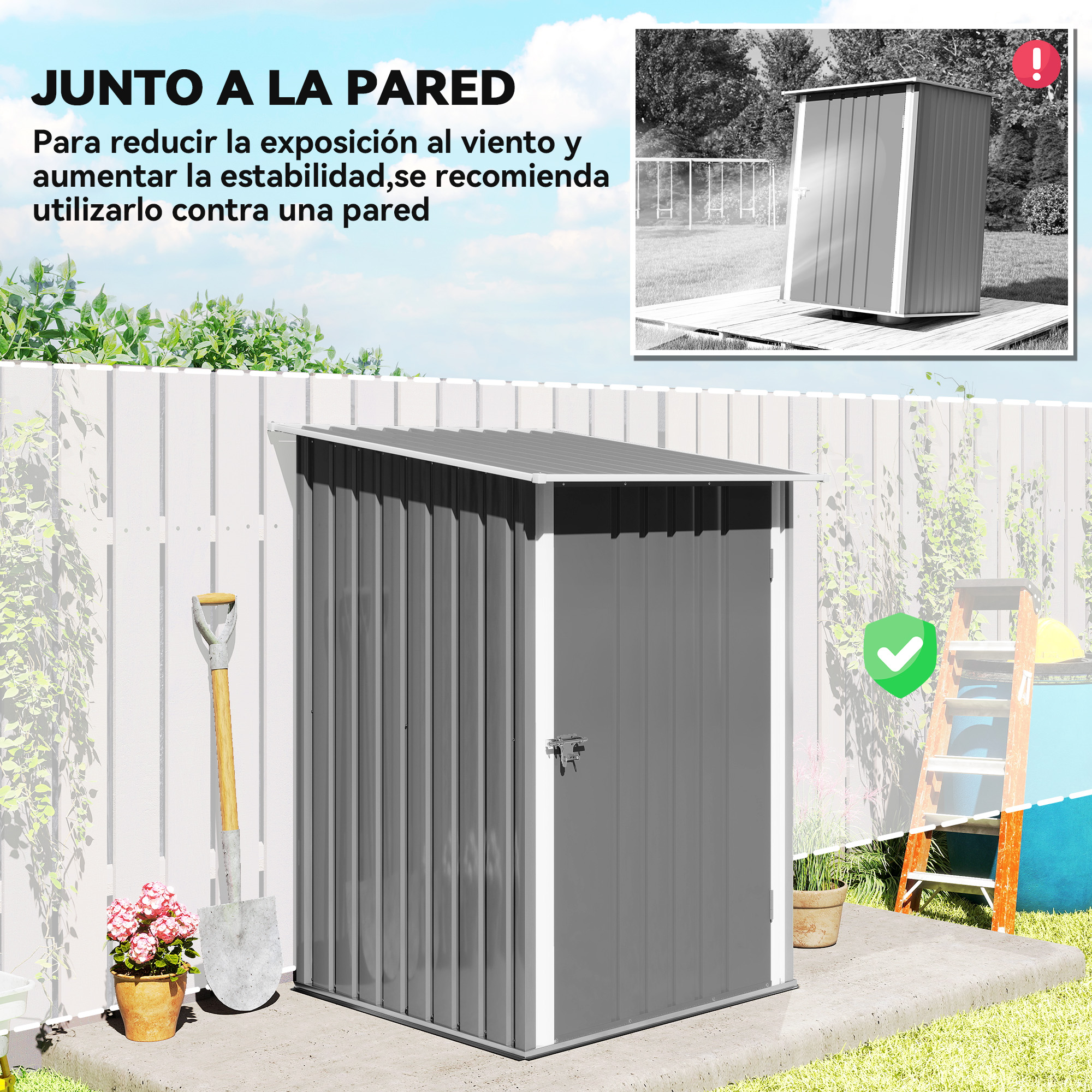 Un cobertizo gris contra una valla blanca. Una pala y macetas en primer plano. Una escalera a la derecha.