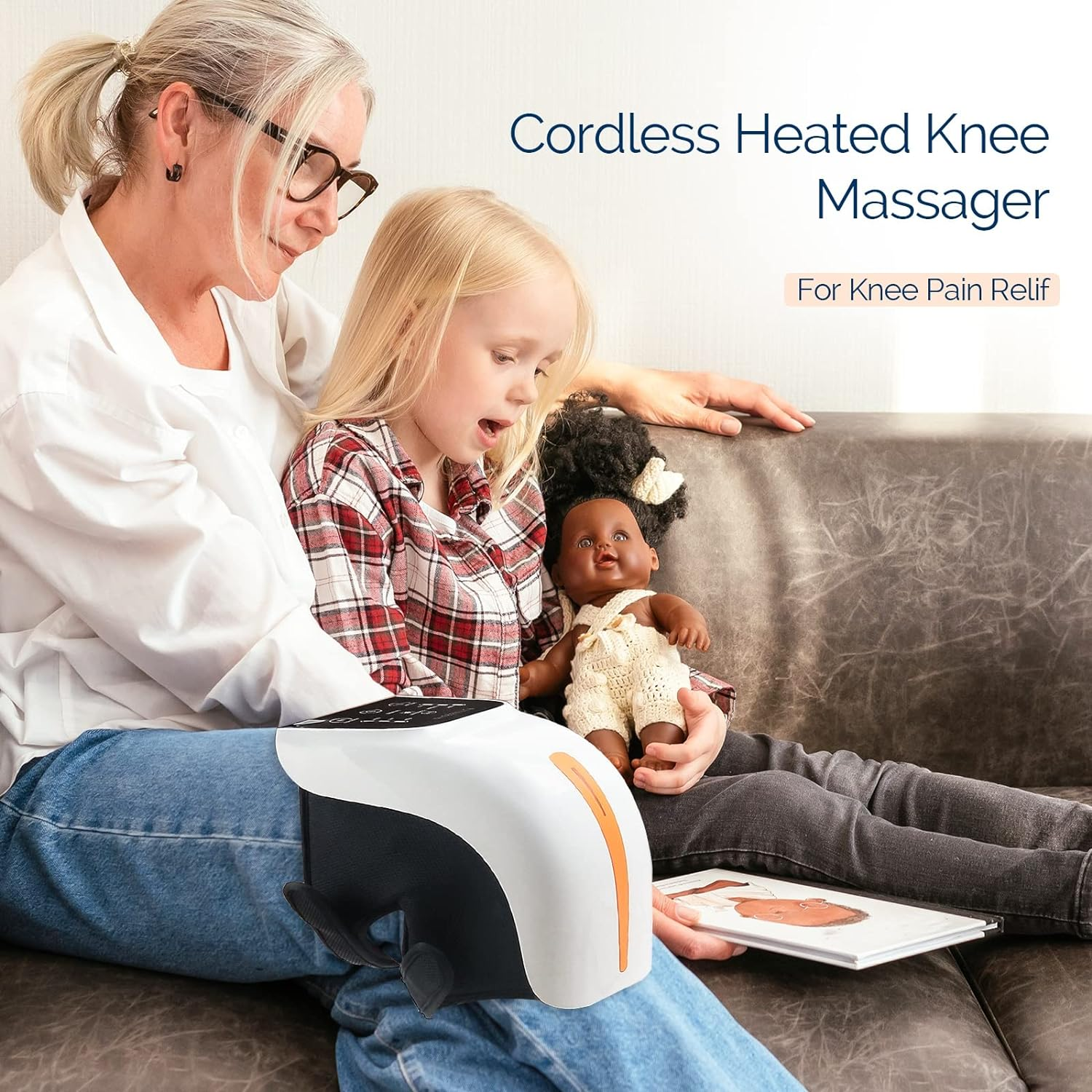 Eine Frau und ein Mädchen sitzen auf einer Couch. Auf dem Bein der Frau befindet sich ein Kniemassagegerät. Sie schauen ein Buch an.
