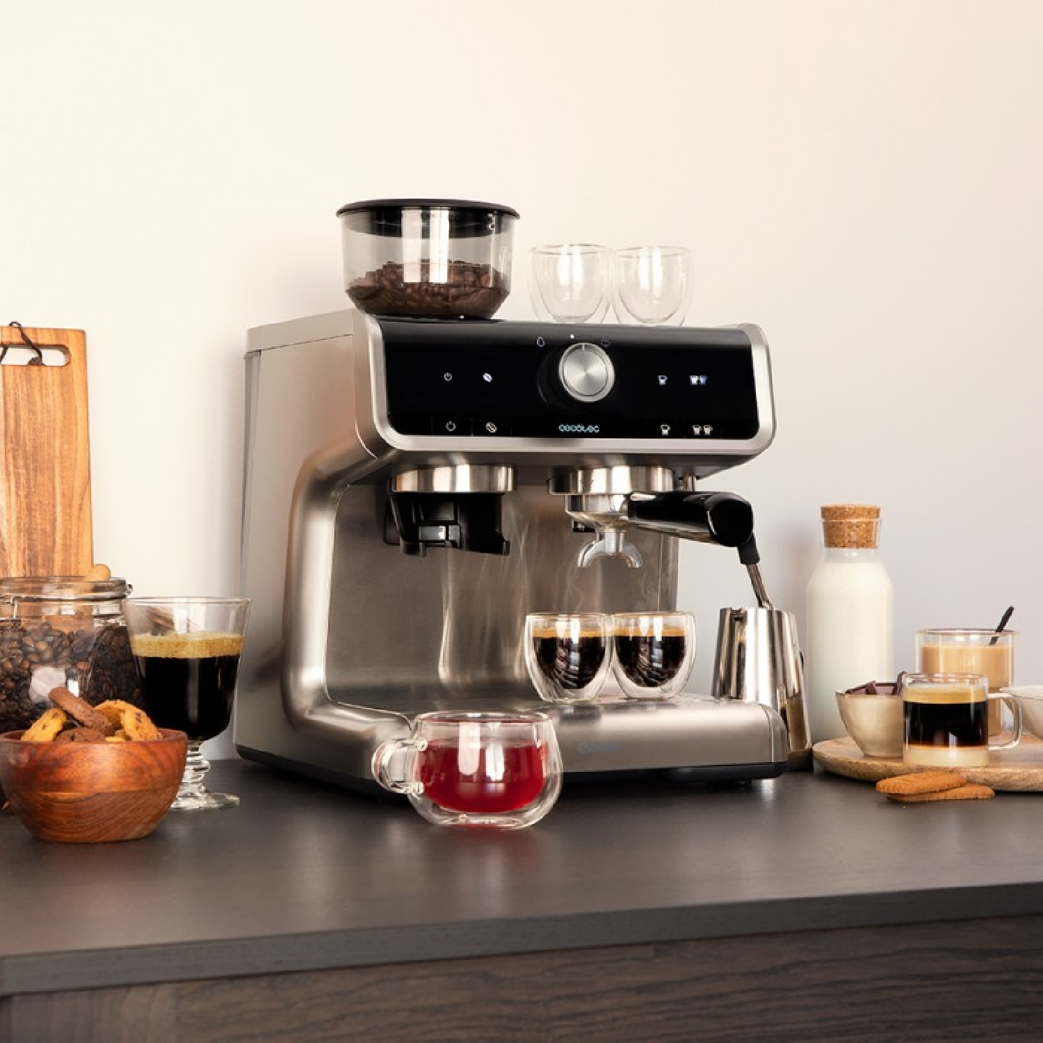 Una macchina da caffè con tazzine, un bicchiere di bevanda rossa, ciotole con biscotti e chicchi di caffè e una bottiglia di latte.