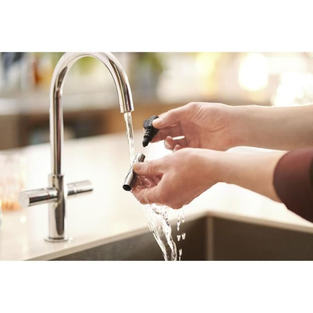 Ręce myją czarną i srebrną część ekspresu do kawy pod bieżącą wodą z chromowanej baterii w kuchni.