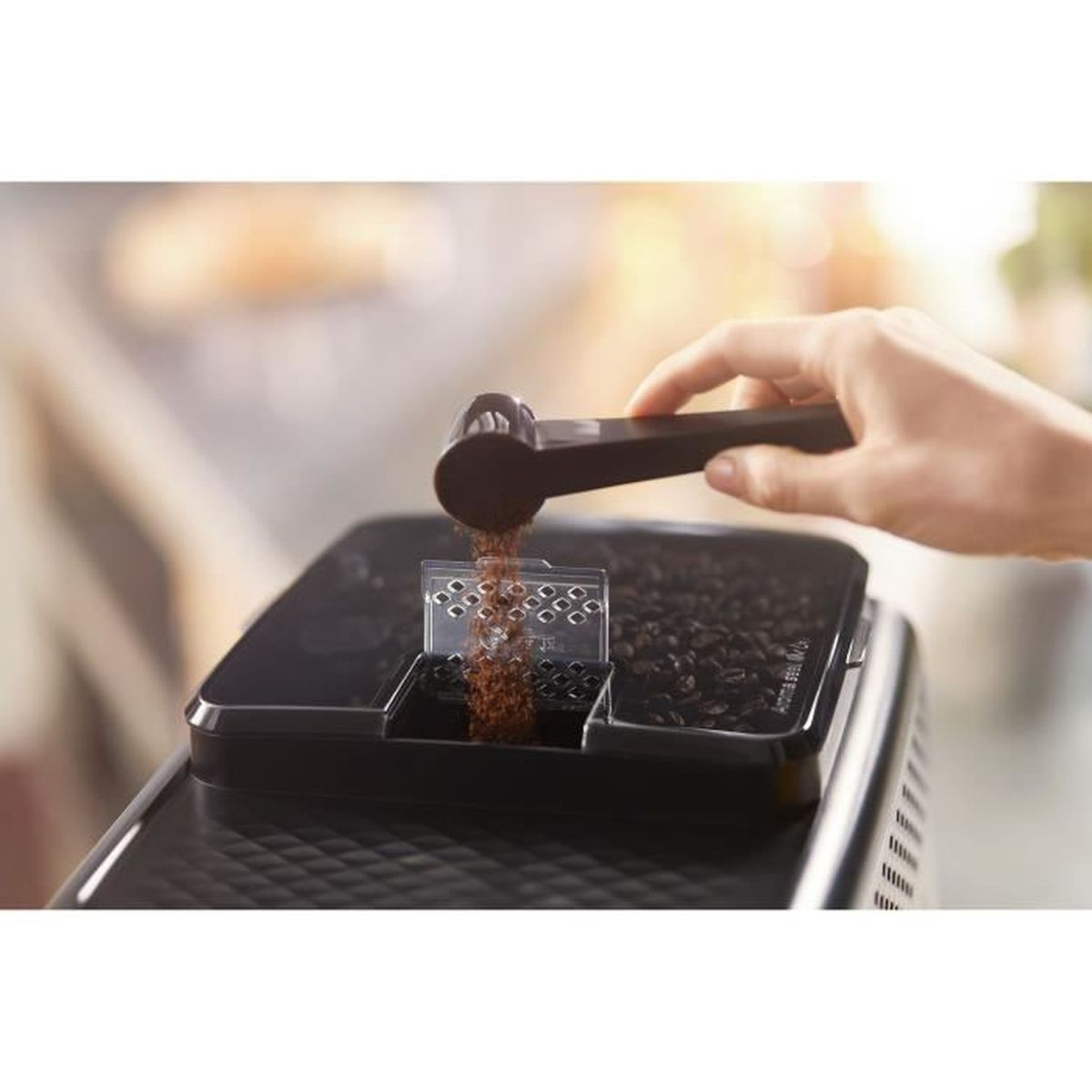 Ręka wsypuje zmieloną kawę z miarki do ekspresu do kawy. Maszyna zawiera ziarna kawy. Tło jest rozmyte.