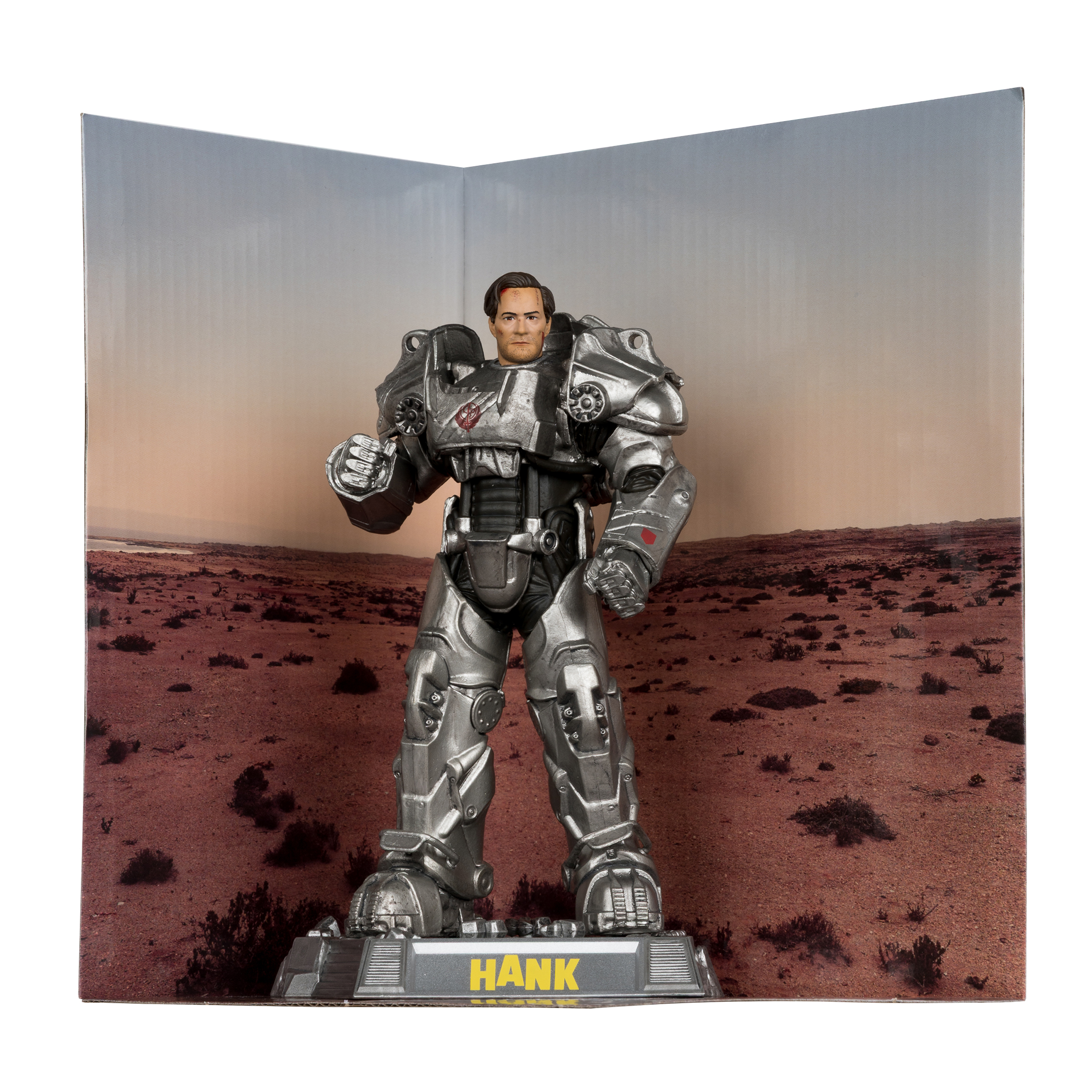 Una figura in armatura d'argento è in piedi su una base con la scritta 'HANK'. Lo sfondo mostra un paesaggio desertico.