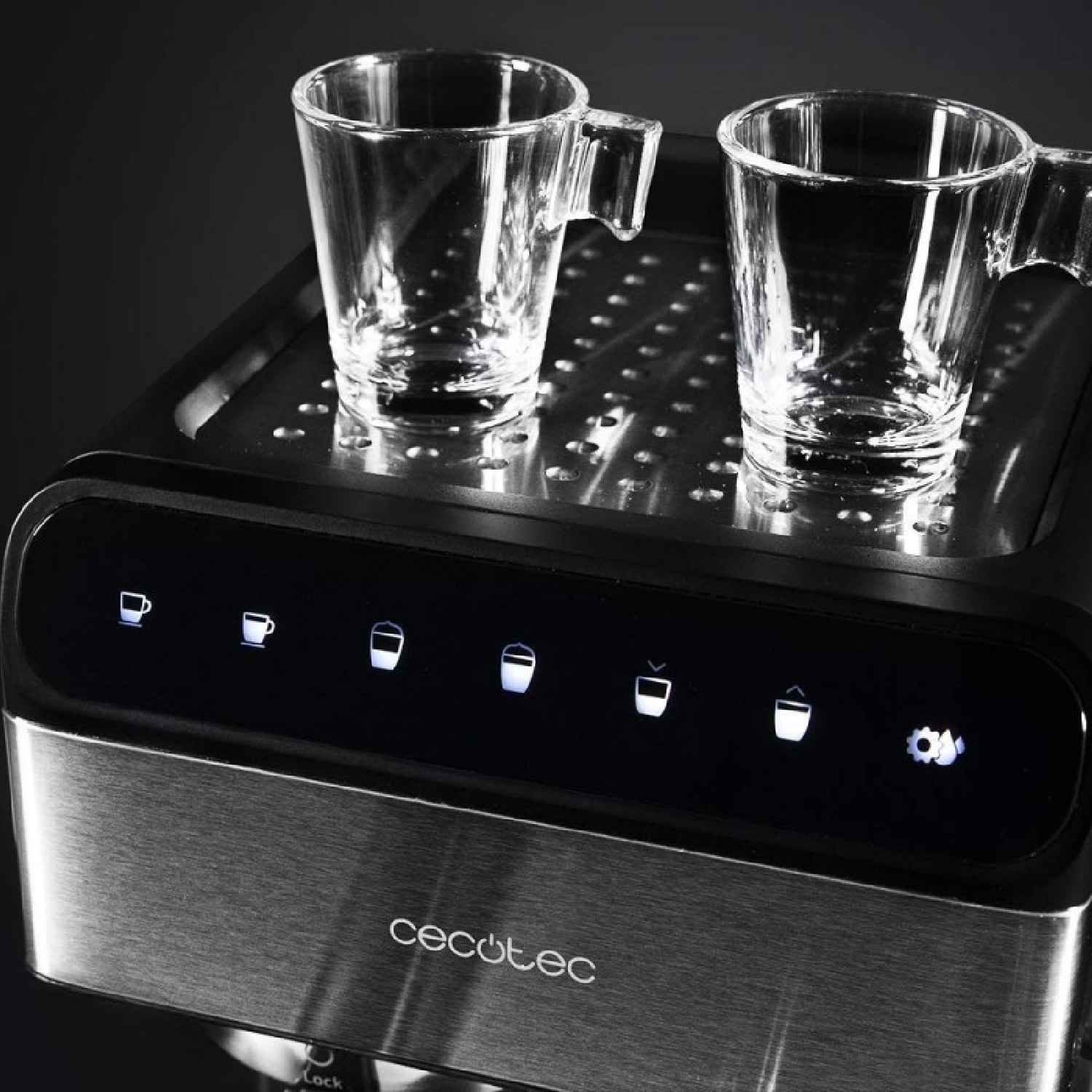 Dos tazas de espresso de vidrio transparente están sobre una máquina de espresso Cecotec. El panel de control de la máquina tiene iconos iluminados.