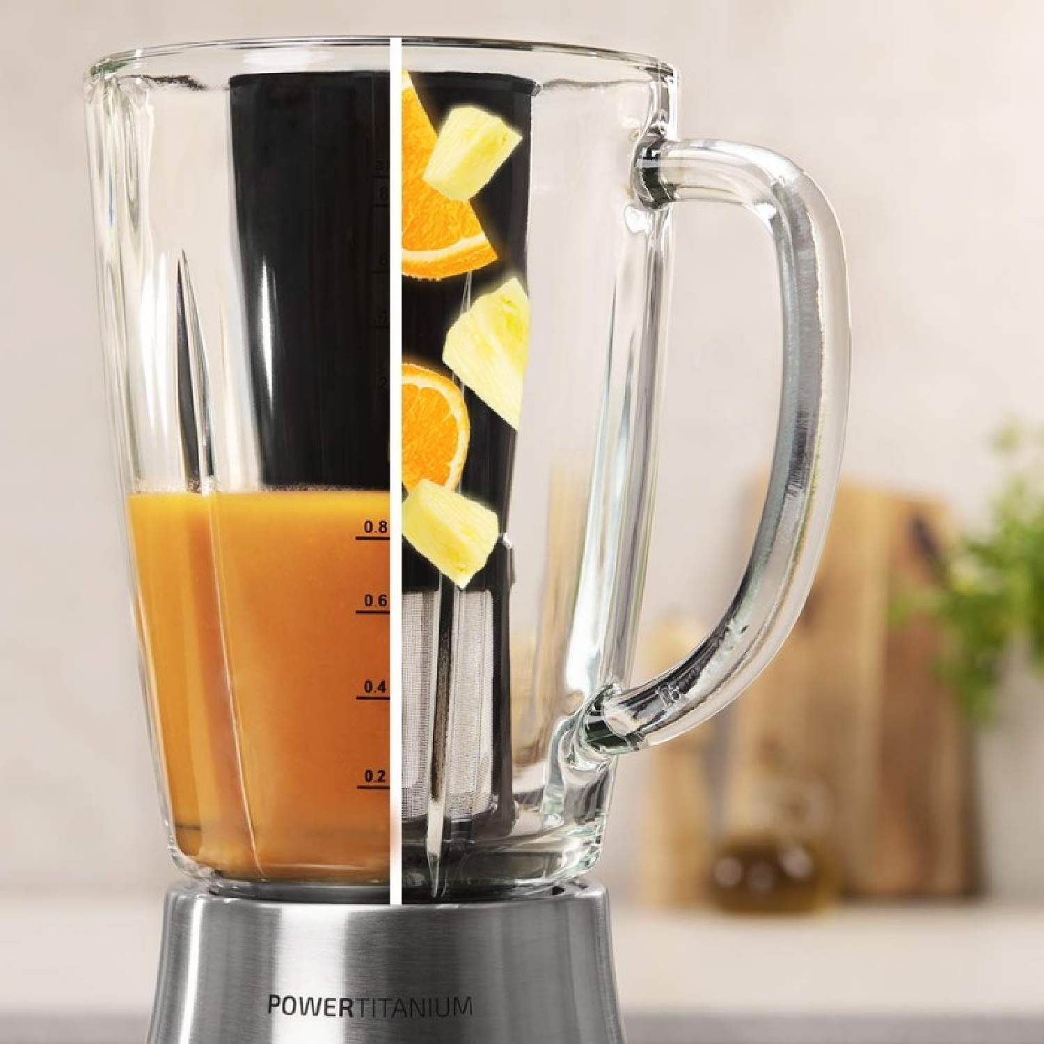 Una licuadora con fruta dentro. El jugo de naranja llena la mitad del vaso. Se ven naranja y piña. La base es plateada.