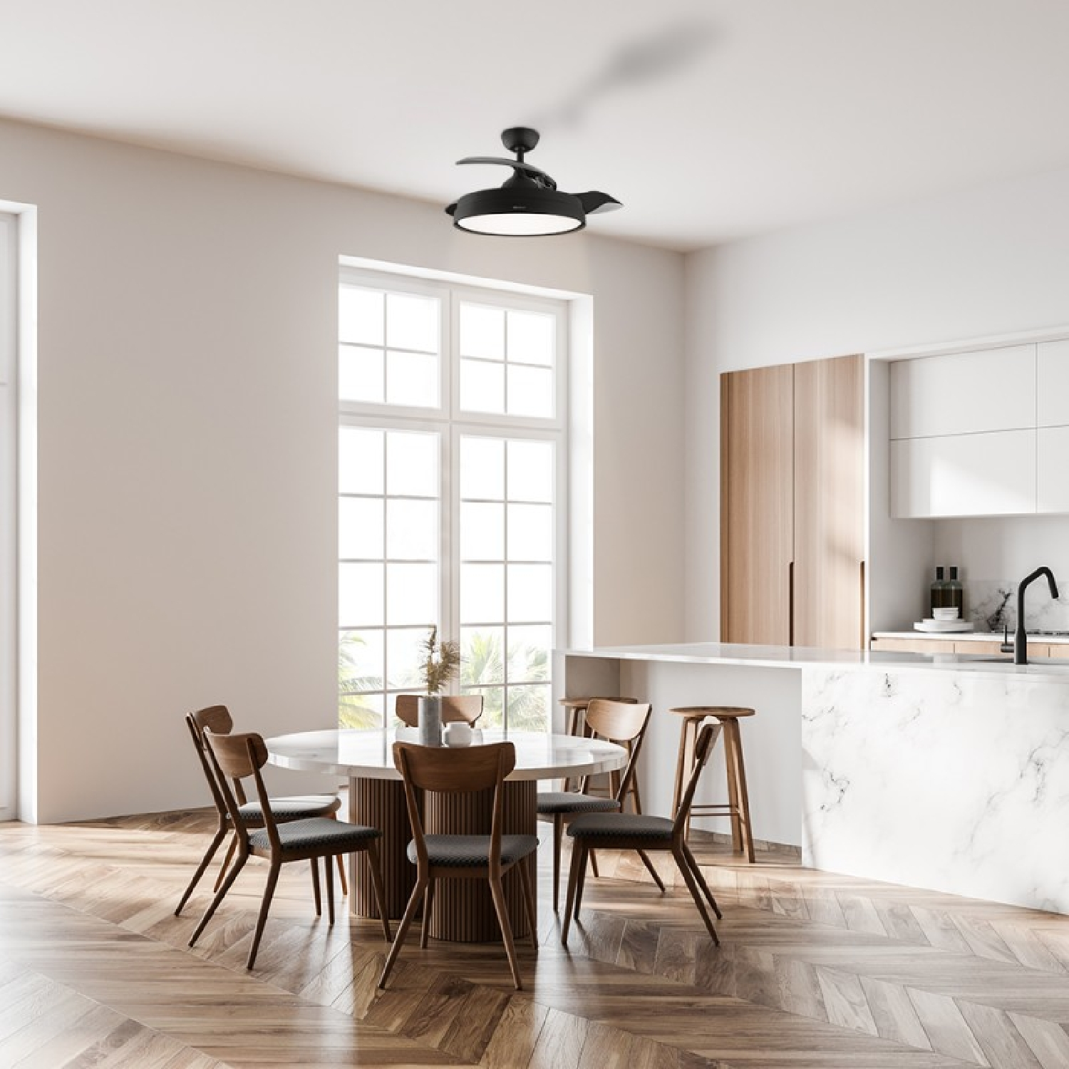 Nowoczesna kuchnia z okrągłym stołem, krzesłami i wentylatorem sufitowym. Kuchnia ma drewniane podłogi i białe ściany. Widoczne jest duże okno.