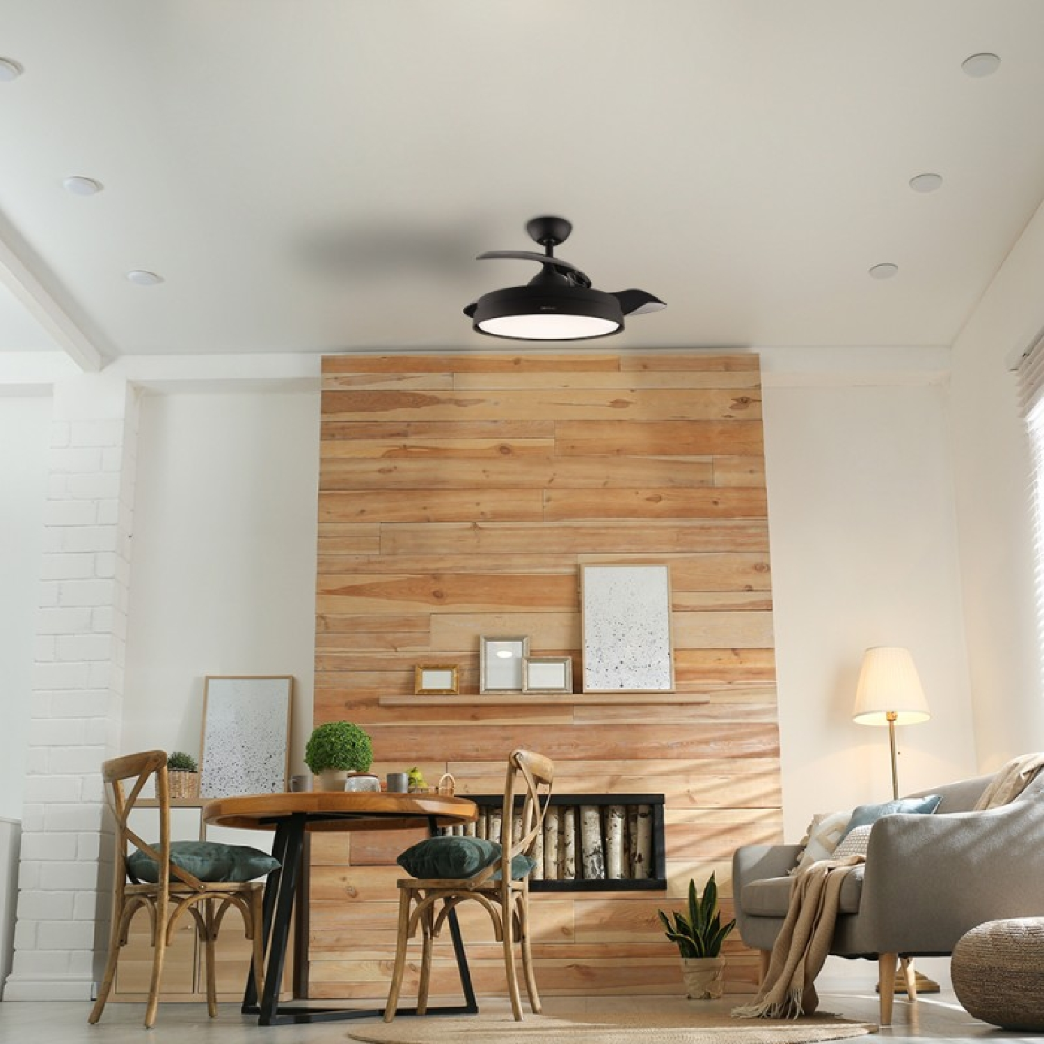 Nowoczesny salon z drewnianą ścianą, okrągłym stołem, krzesłami, sofą i wentylatorem sufitowym.