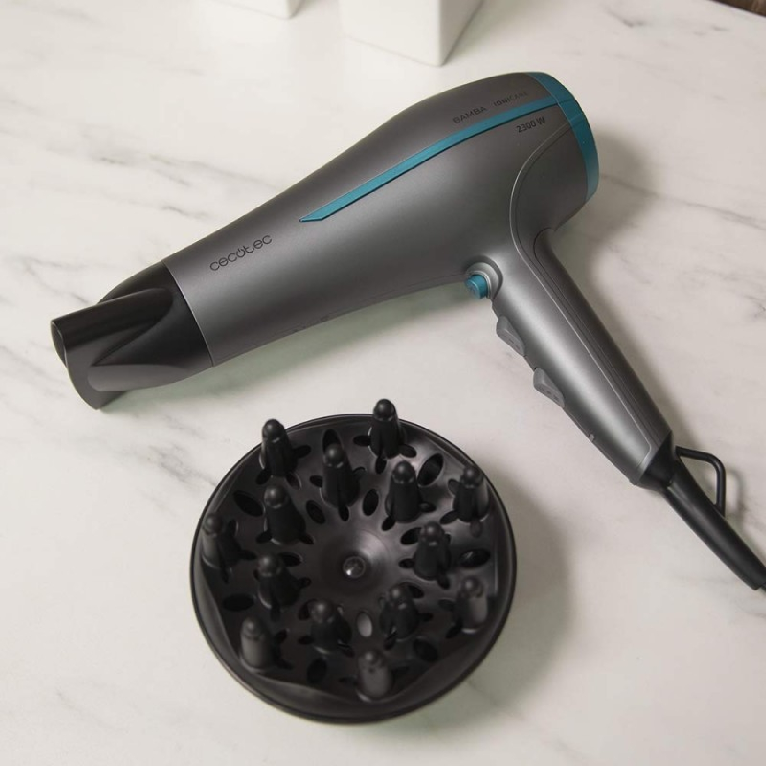 Un asciugacapelli grigio con dettagli blu e un diffusore nero su una superficie di marmo bianco. L'asciugacapelli è marchiato 'cecotec'.