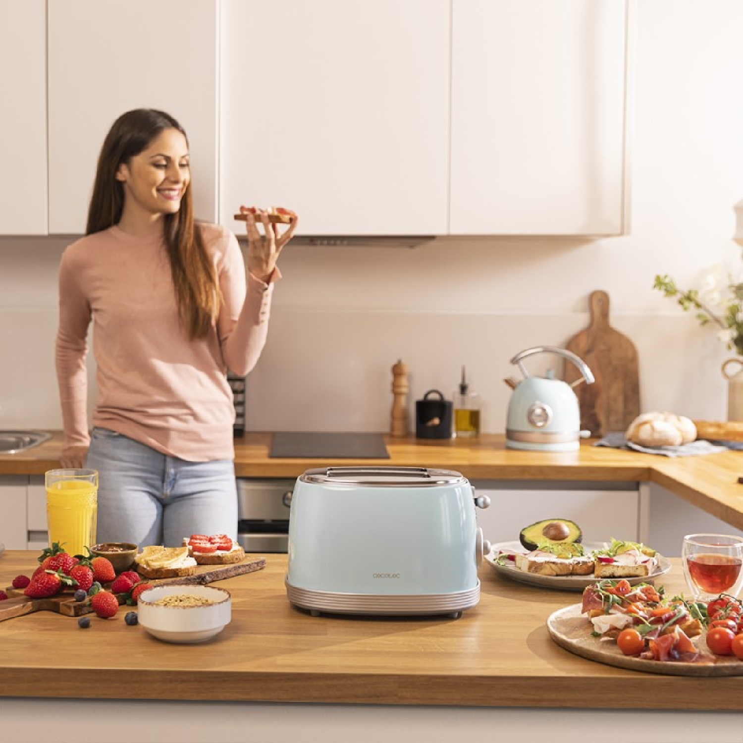 Kobieta w kuchni z śniadaniem. Tosty, owoce i toster na blacie. Trzyma tost.