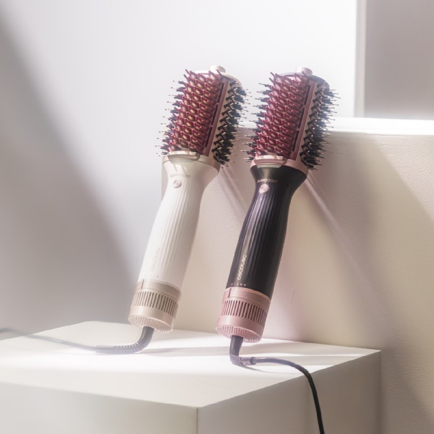 Due spazzole per capelli, una bianca, una nera. Entrambe hanno setole rosse e sono posizionate su una superficie bianca con sfondo bianco.