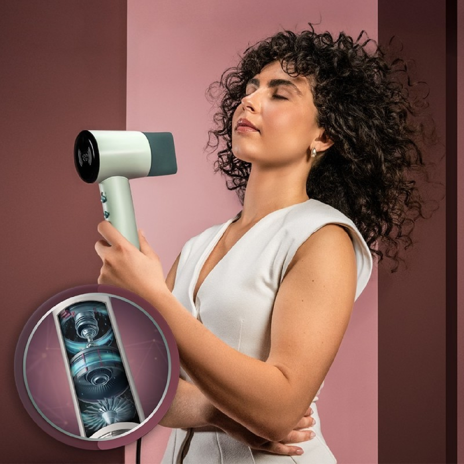 Eine Frau mit lockigem Haar hält einen Fön, die Augen geschlossen. Ein Diagramm zeigt den Mechanismus.