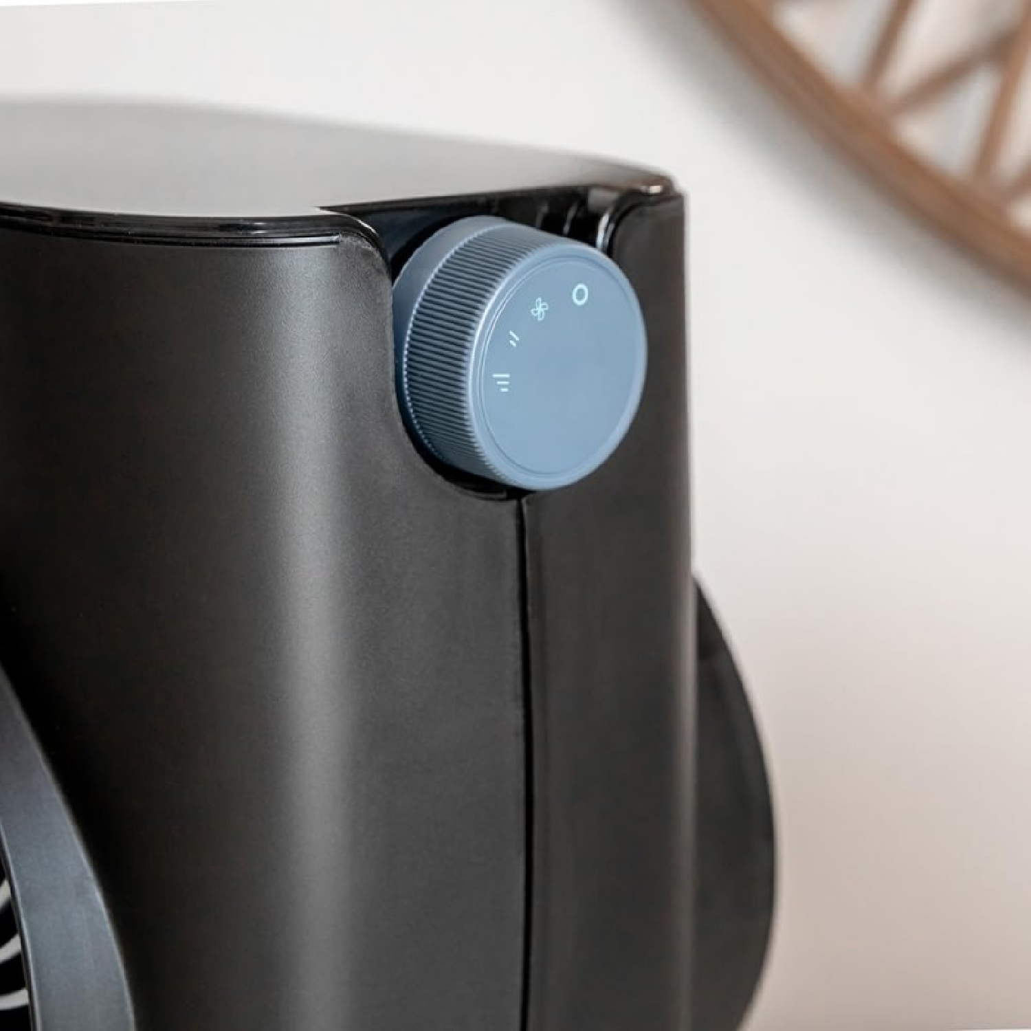 Zbliżenie czarnego wentylatora. Szara tarcza z symbolami z boku. Tło jest białe i element drewniany.