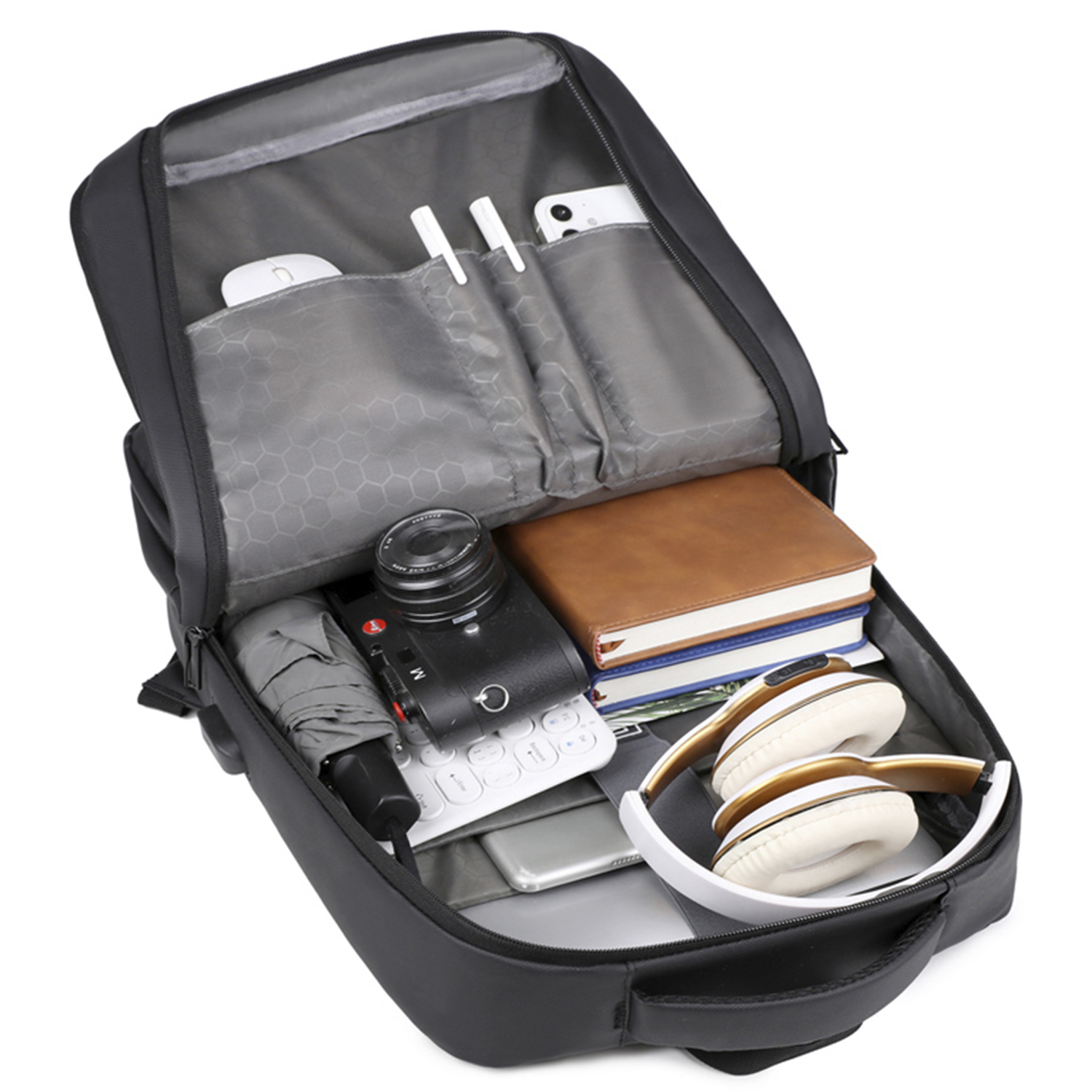 Zaino aperto pieno di oggetti: fotocamera, taccuino, ombrello, cuffie, mouse, penne, smartphone e tastiera. Borsa nera con interno grigio.