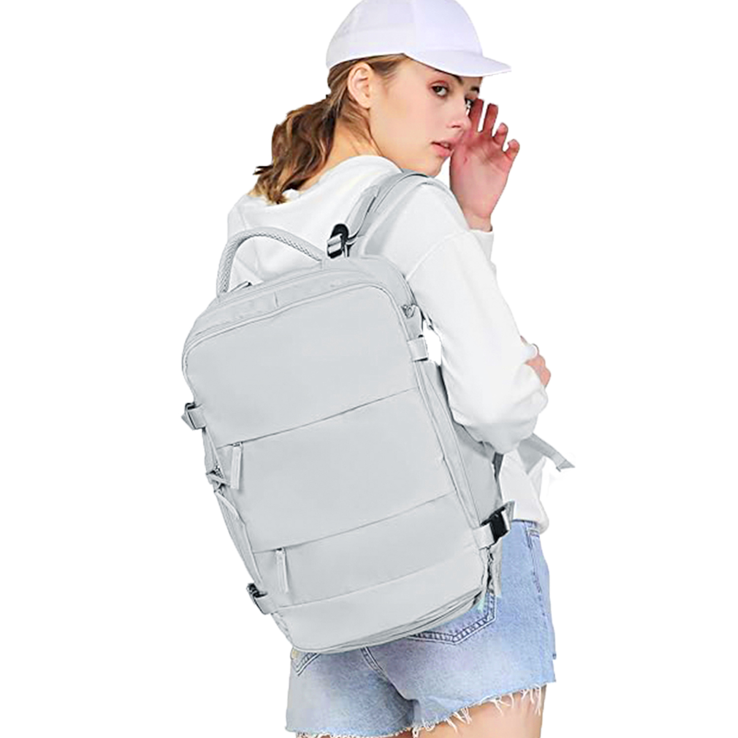 Una donna con un berretto bianco, una felpa e pantaloncini di jeans, che porta uno zaino grigio chiaro, che guarda oltre la spalla.