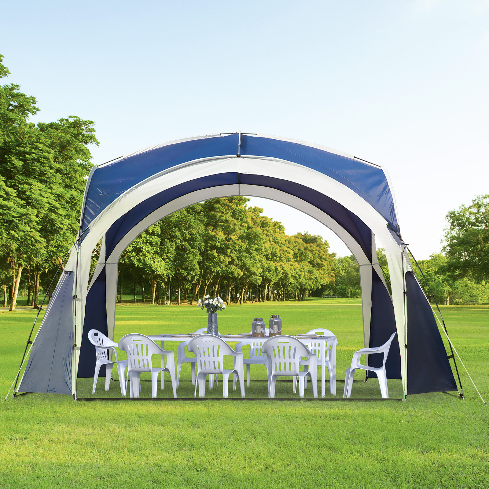 Una glorieta con mesa y sillas está instalada en un césped verde con árboles al fondo.