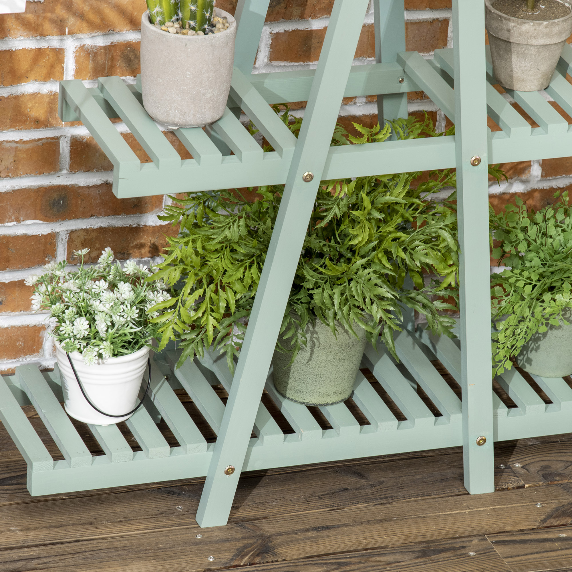 Un estante de madera verde menta sostiene plantas en macetas. Una pared de ladrillo sirve de fondo y suelo de madera.
