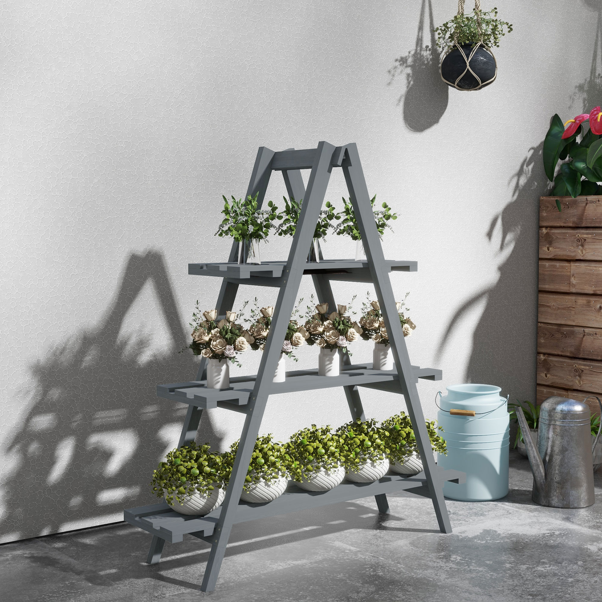 Un estante de madera gris para plantas con flores y plantas. Una planta colgante en la pared. Una regadera y un cubo de leche.