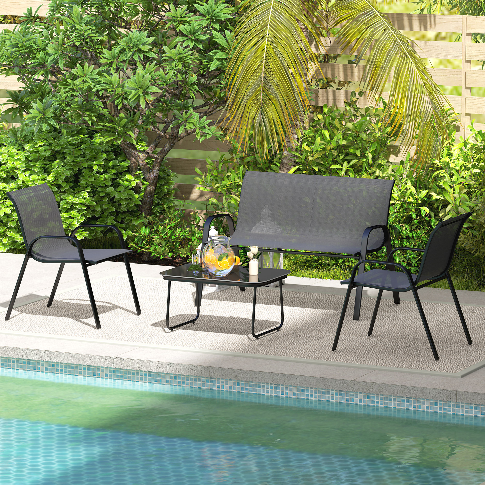 Muebles de patio: sillas, sofá y mesa. Piscina en primer plano, exuberante vegetación y valla al fondo. Día soleado.
