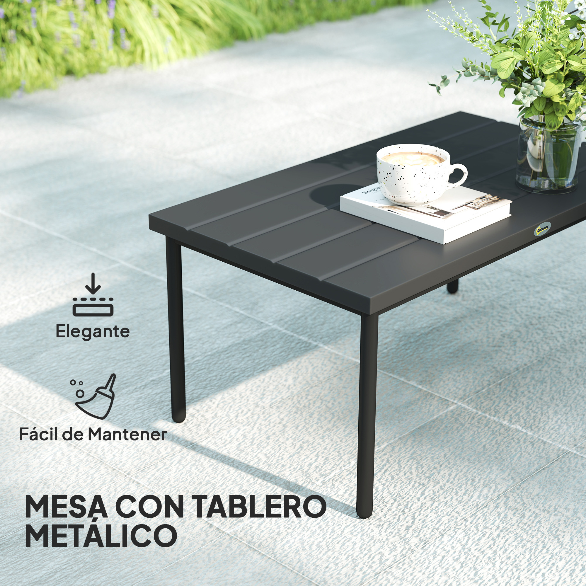Una mesa de metal gris oscuro con una taza de café, un libro y flores. La mesa está en un patio claro.