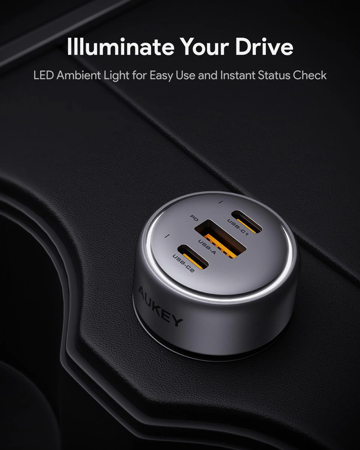 Un caricatore per auto argentato con porte USB è nella console di un'auto. Il caricatore è etichettato AUKEY. Testo in alto: Illumina la tua guida.