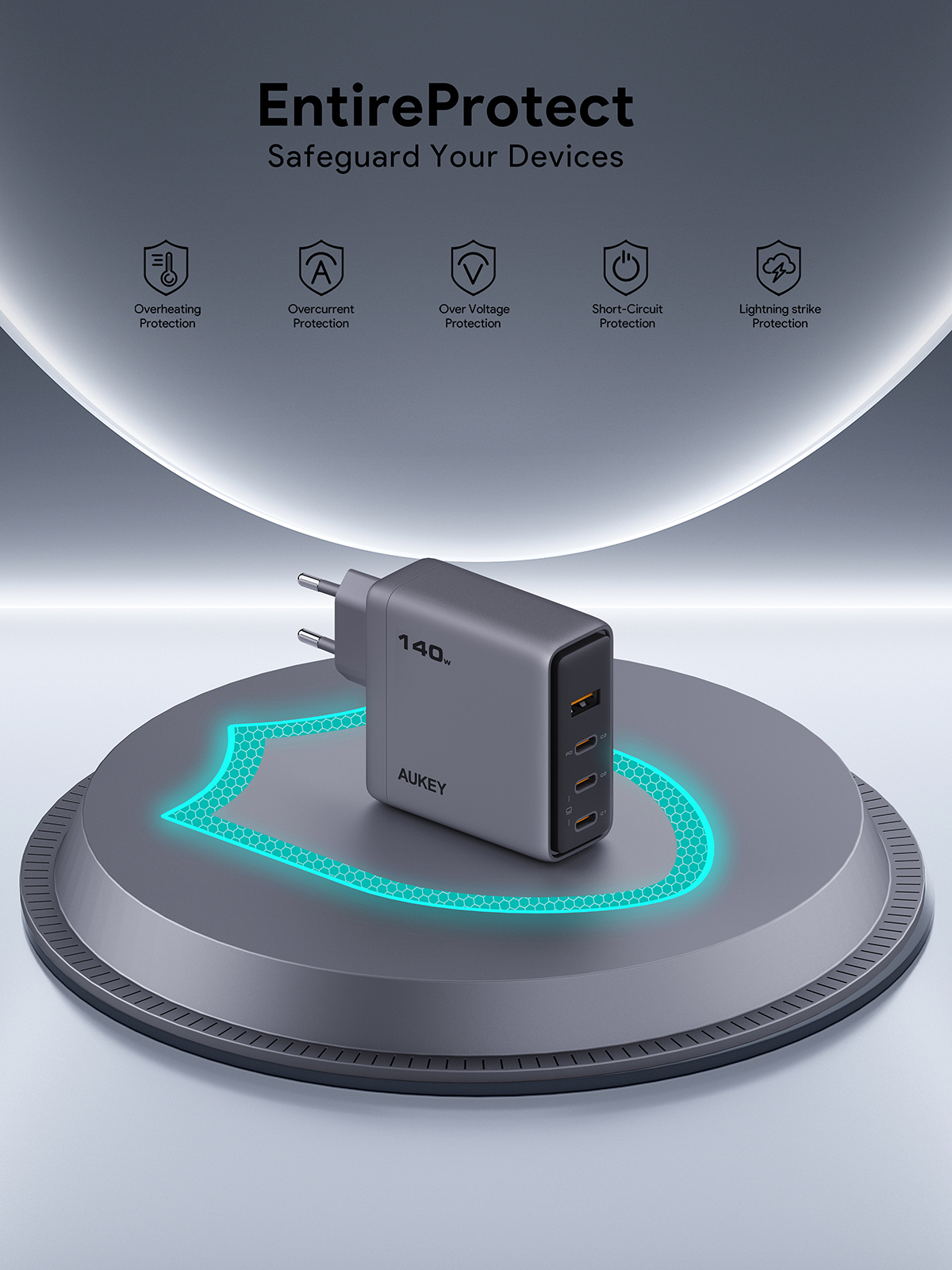 Un cargador AUKEY gris sobre una plataforma. Tiene cuatro puertos y está etiquetado como 140W. El fondo muestra iconos de seguridad.