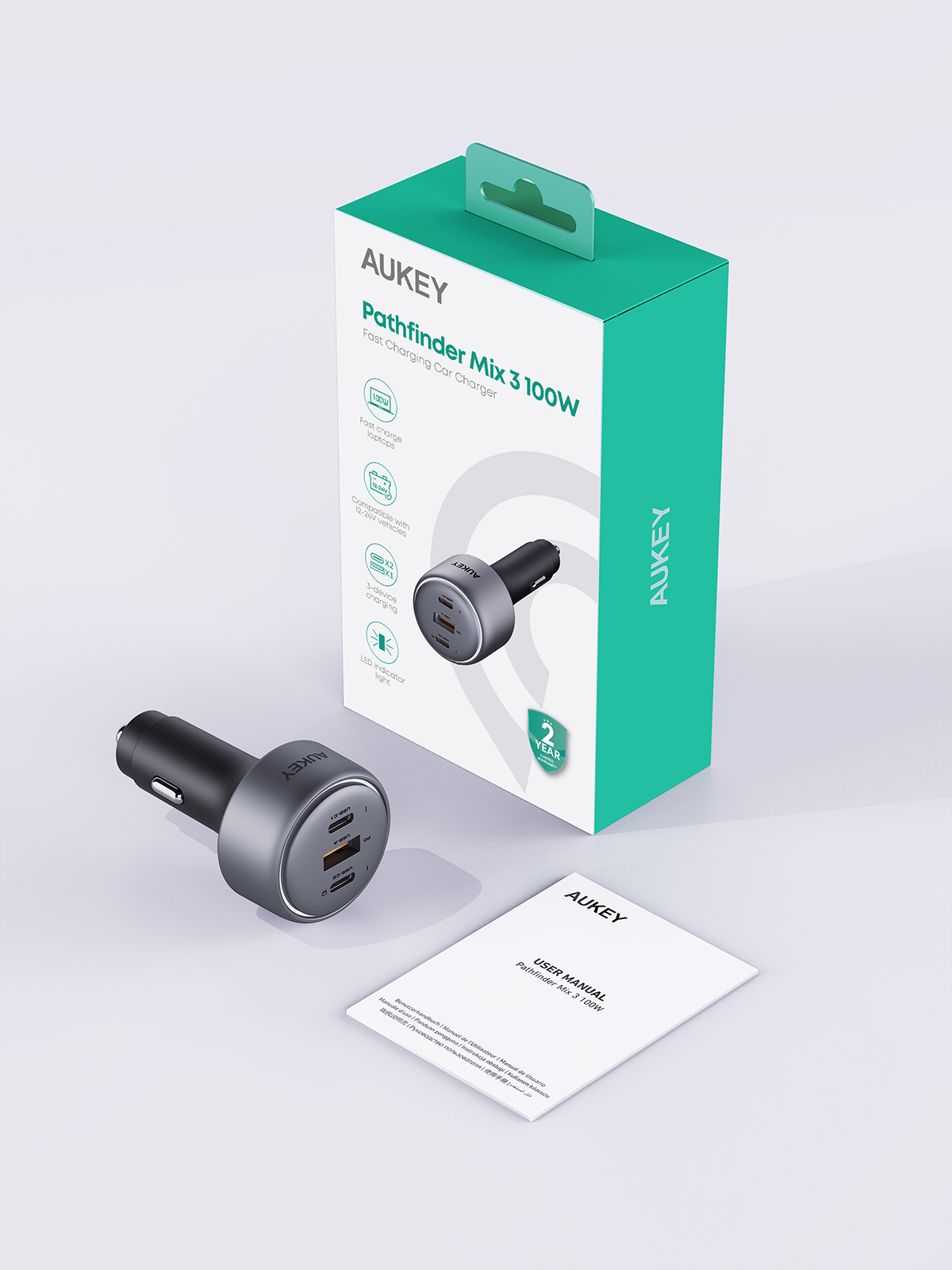 Un caricabatterie per auto AUKEY Pathfinder Mix 3 100W, scatola e manuale utente su una superficie bianca. Il caricabatterie è nero e argento.