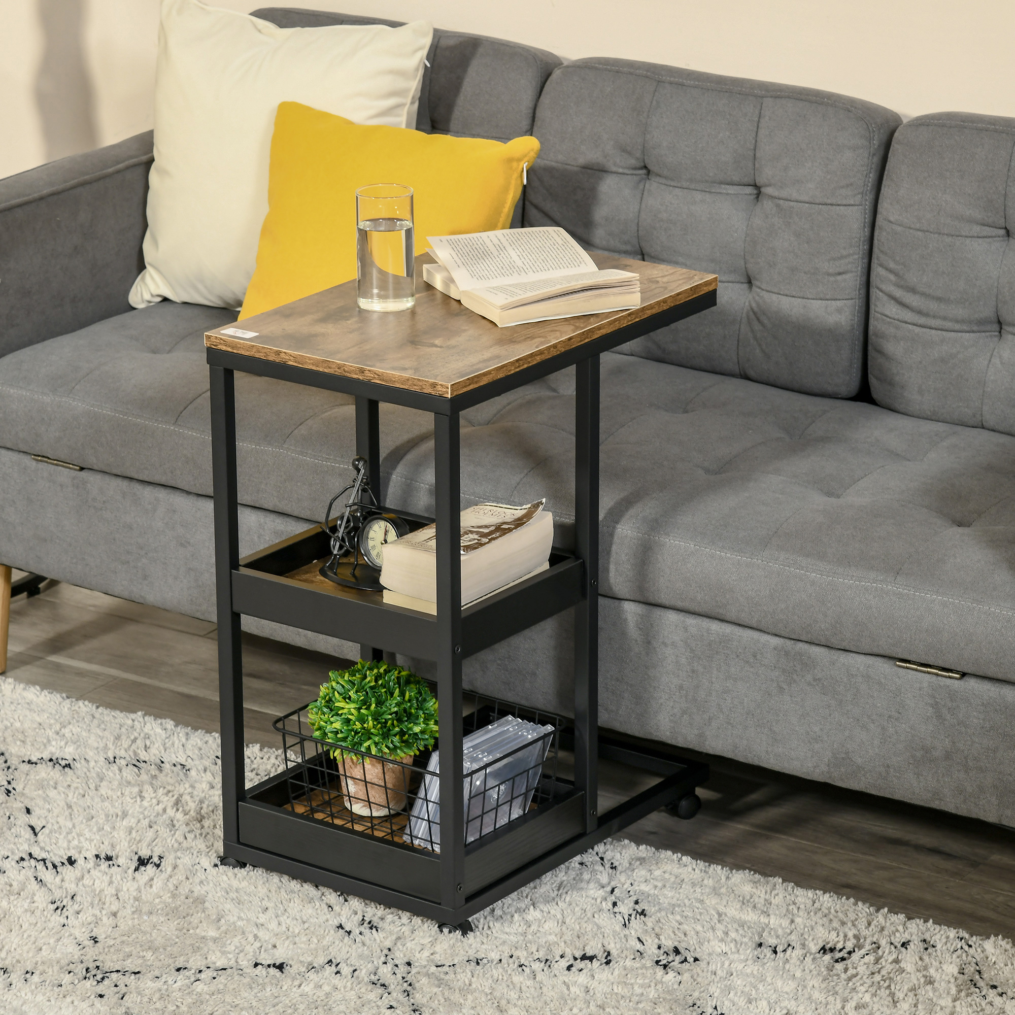 Una mesa auxiliar con libros, un vaso de agua y una planta junto a un sofá gris y una alfombra.