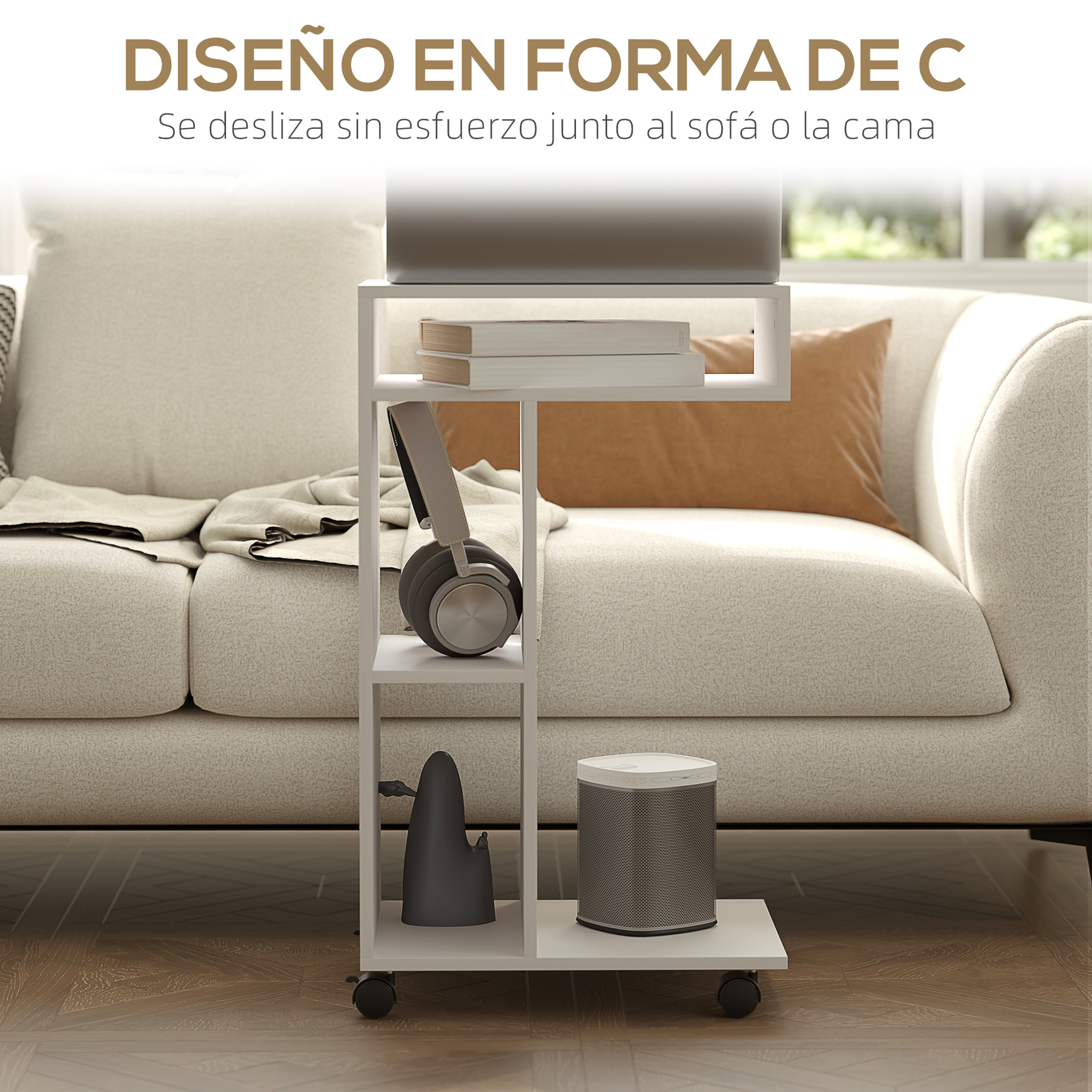 Una mesa auxiliar blanca en forma de C con una computadora portátil, libros, auriculares y un altavoz, junto a un sofá beige.