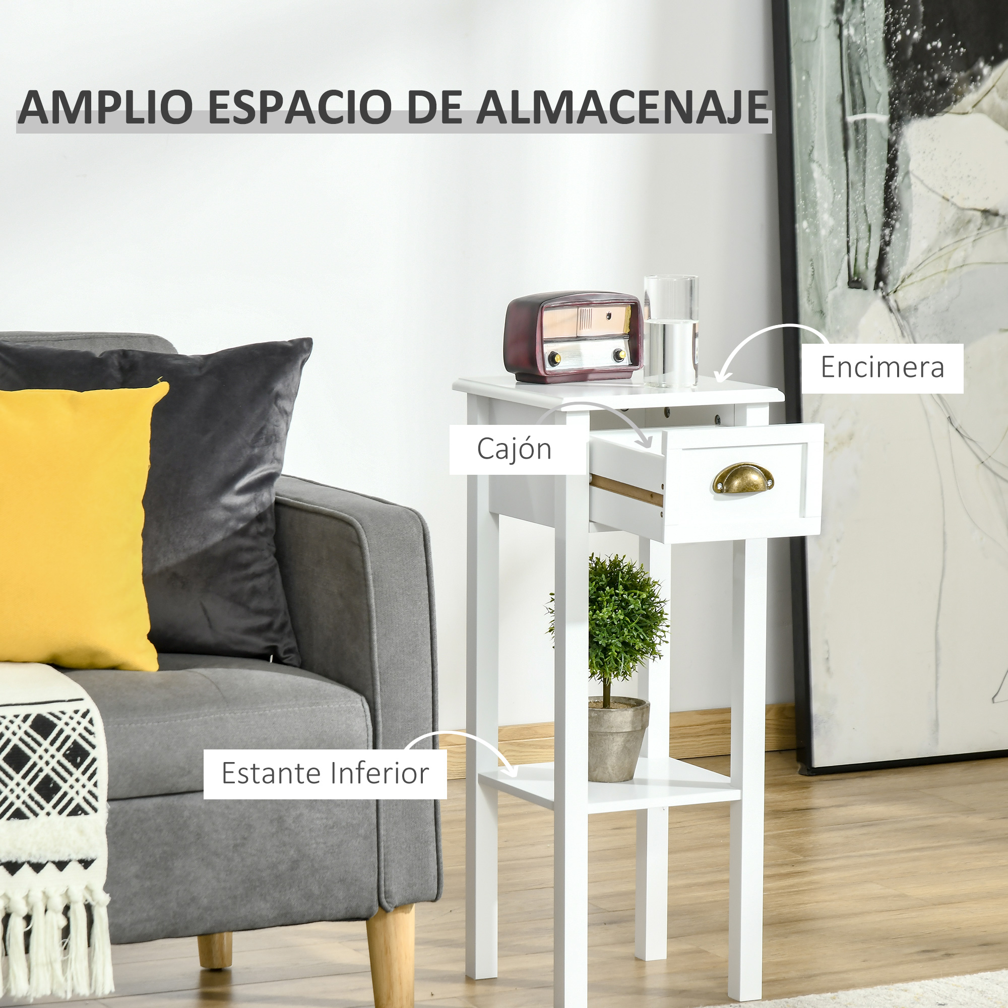 Mesa auxiliar blanca con cajón abierto, planta y radio encima. Sofá gris a la izquierda.