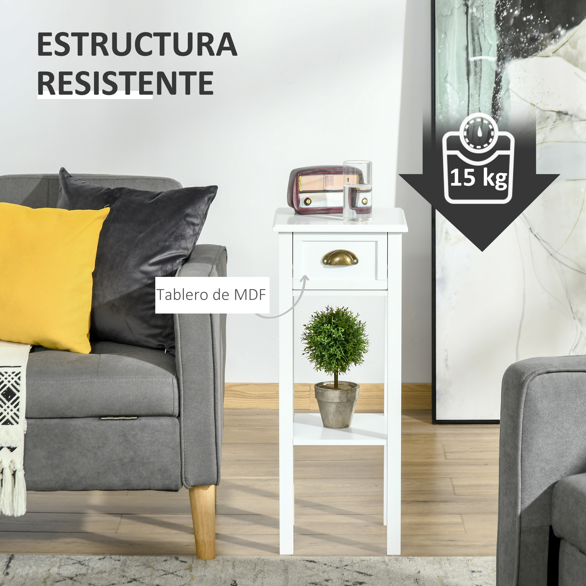 Una mesa auxiliar blanca con cajón. Encima hay una planta, una radio y vasos. Un sofá y almohadas a la izquierda.