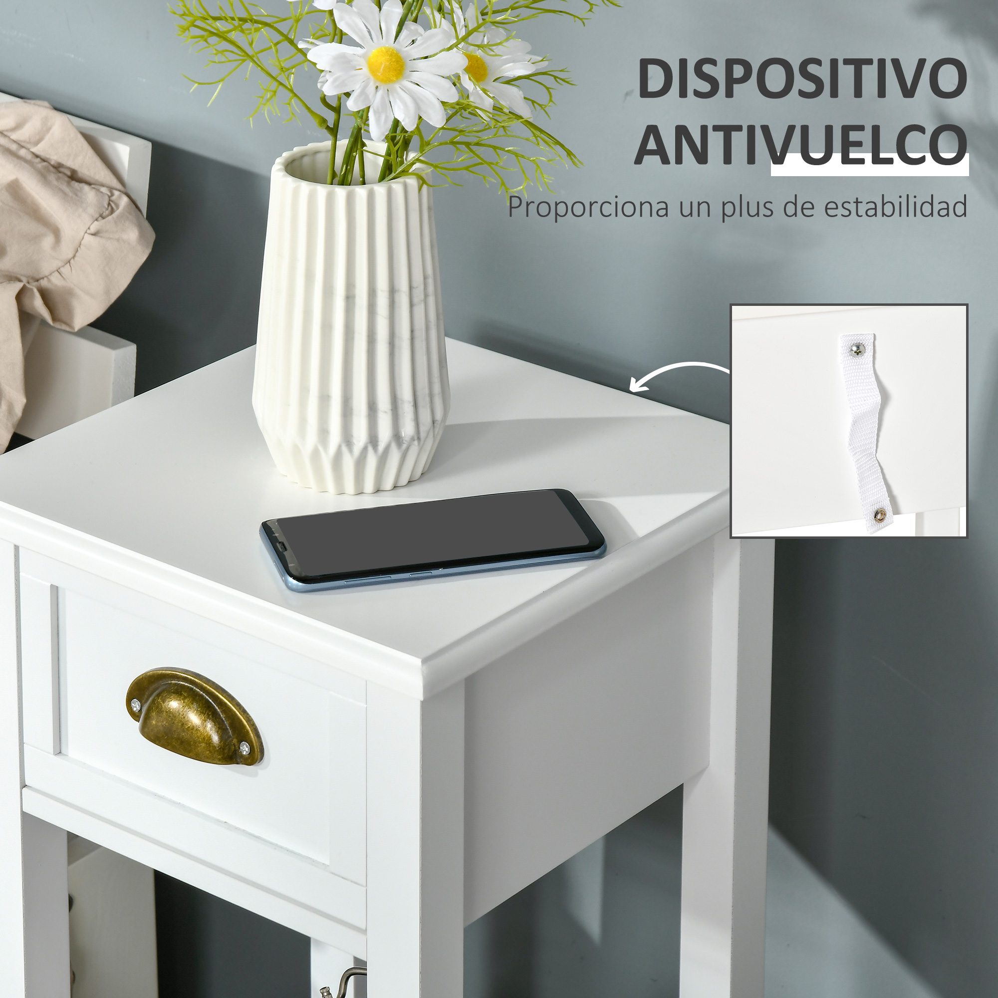 Mesita de noche blanca con cajón, teléfono y jarrón con flores. Texto en español en la pared.