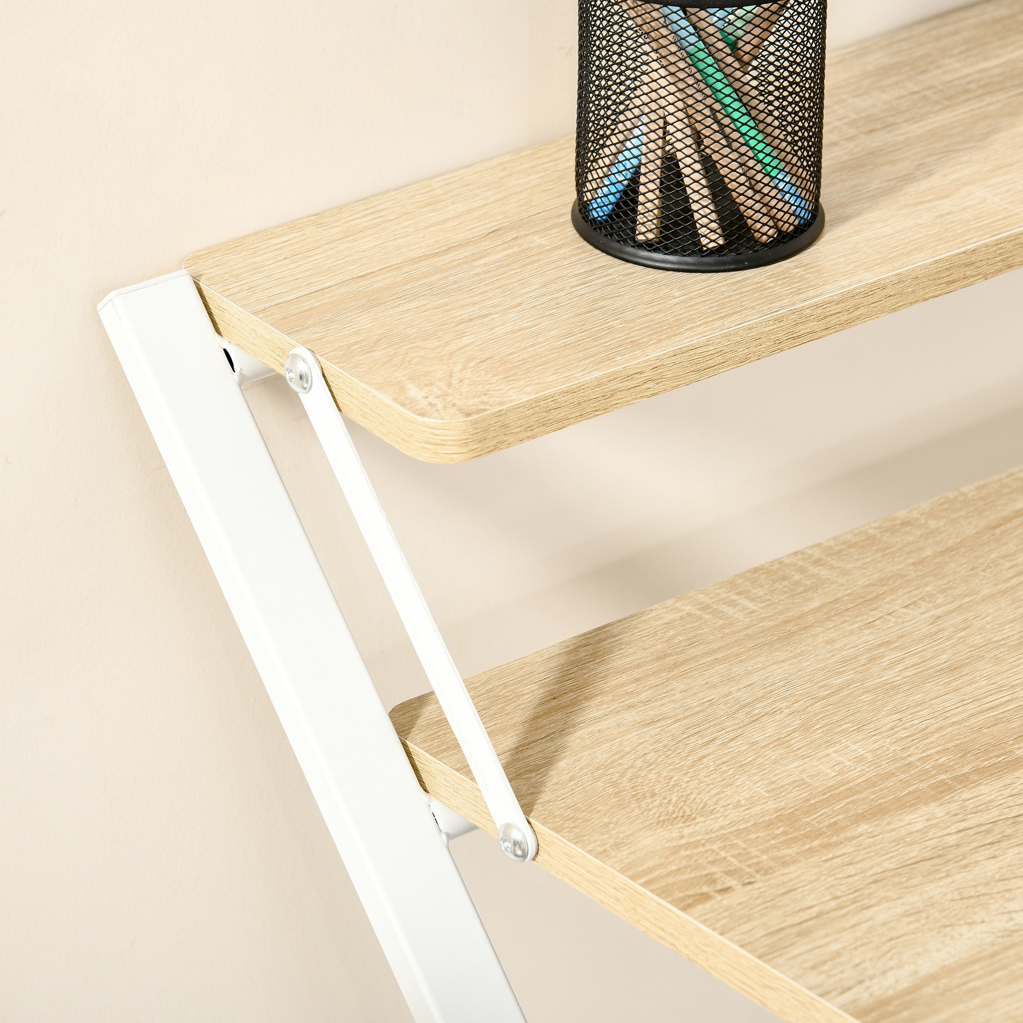 Estantes de madera con un portalápices de malla negra. Soporte de metal blanco. Pared beige al fondo.