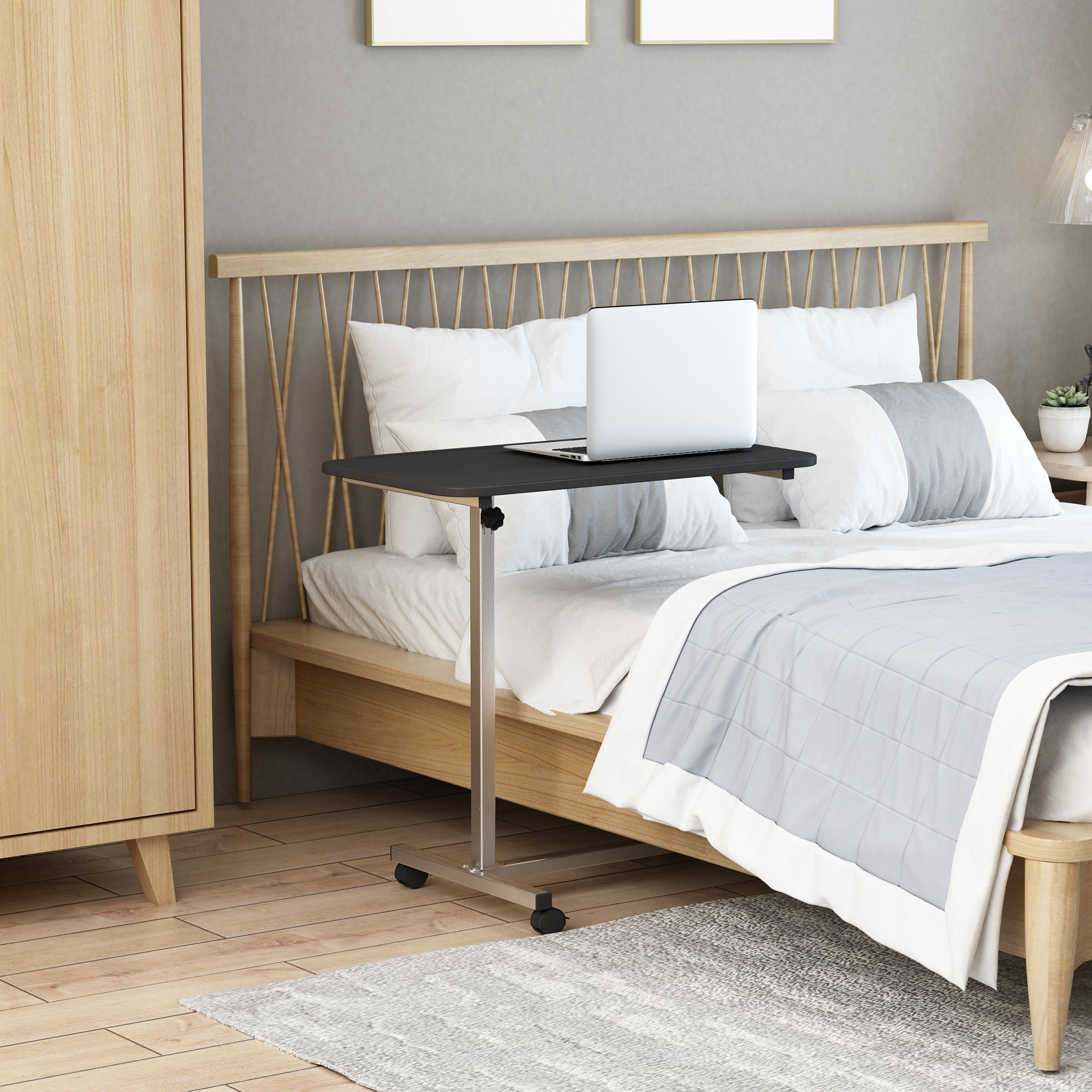 Una escena de dormitorio con una cama, un portátil sobre una mesa y un armario de madera. La cama tiene ropa de cama blanca y gris.
