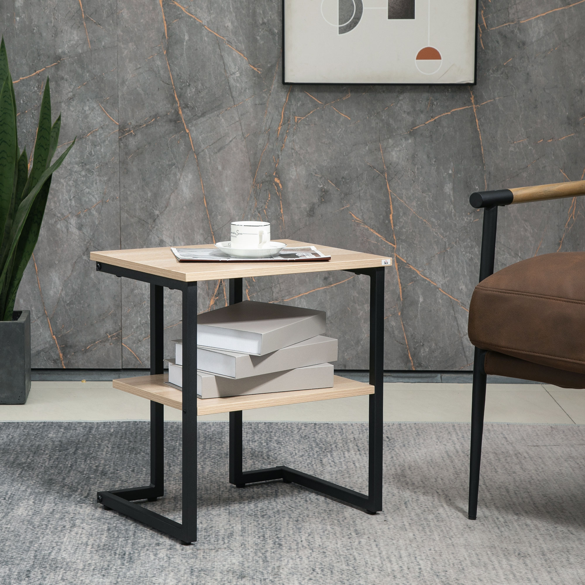 Una mesa auxiliar con libros, una taza y una silla. El fondo es una pared texturizada con una pintura y una planta en maceta.
