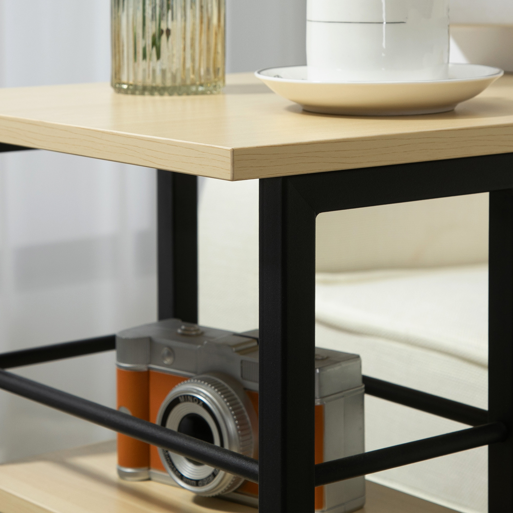 Una mesa con una cámara, una taza y un jarrón. La cámara es naranja y plateada. La taza es blanca, el jarrón ámbar.